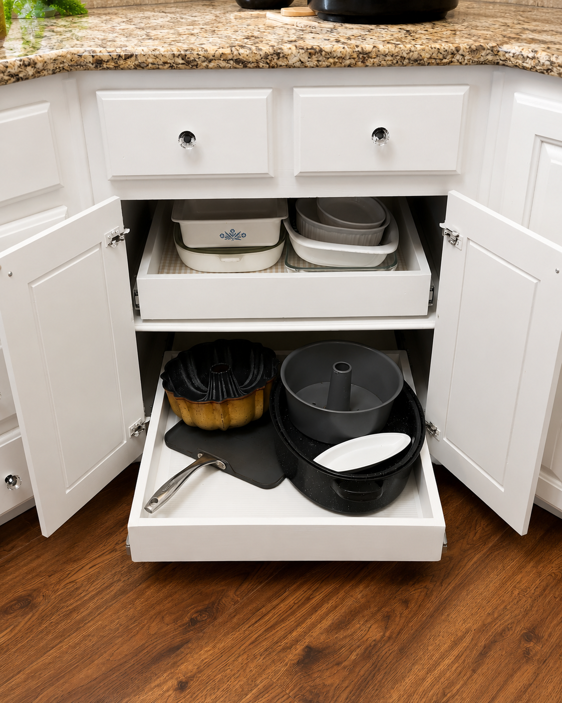 Open kitchen cabinet with baking dishes, a Bundt pan, and a slow cooker on the bottom, with a granite countertop above.
