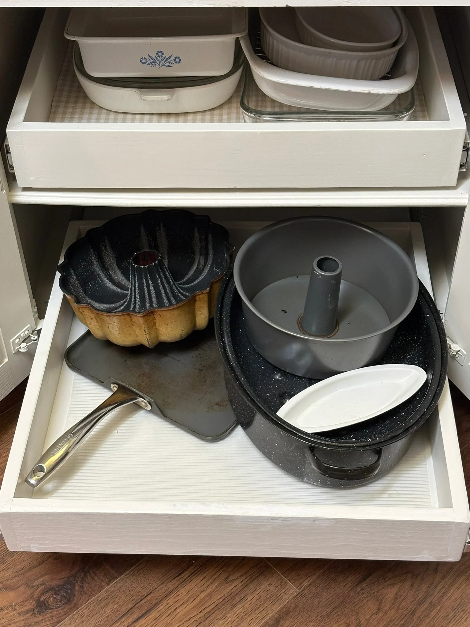 Open kitchen drawer with baking pans, a cake pan, a bundt pan, and a bundt cake pan.