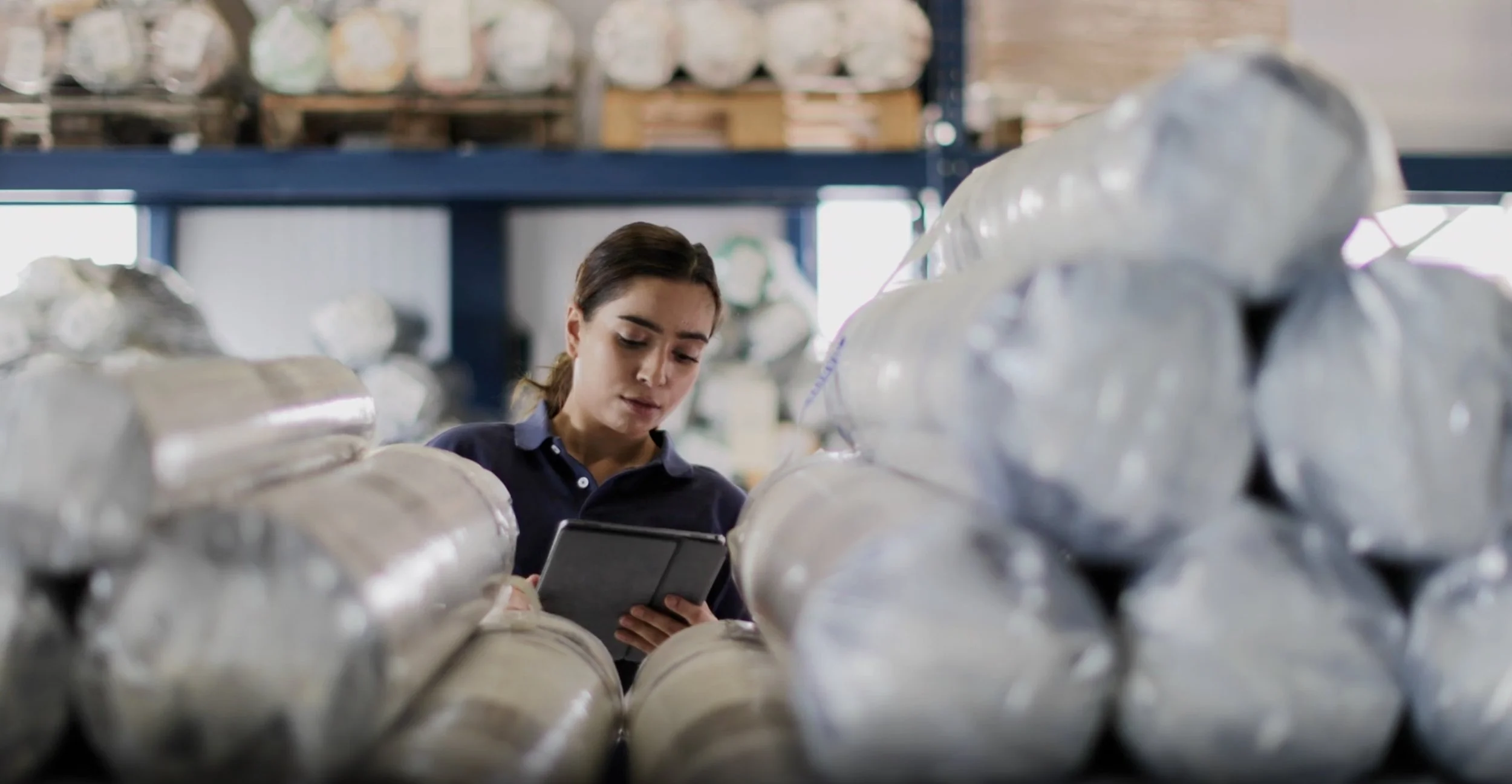 A woman working in a warehouse, inspecting packages ready to be sold at Amazon.