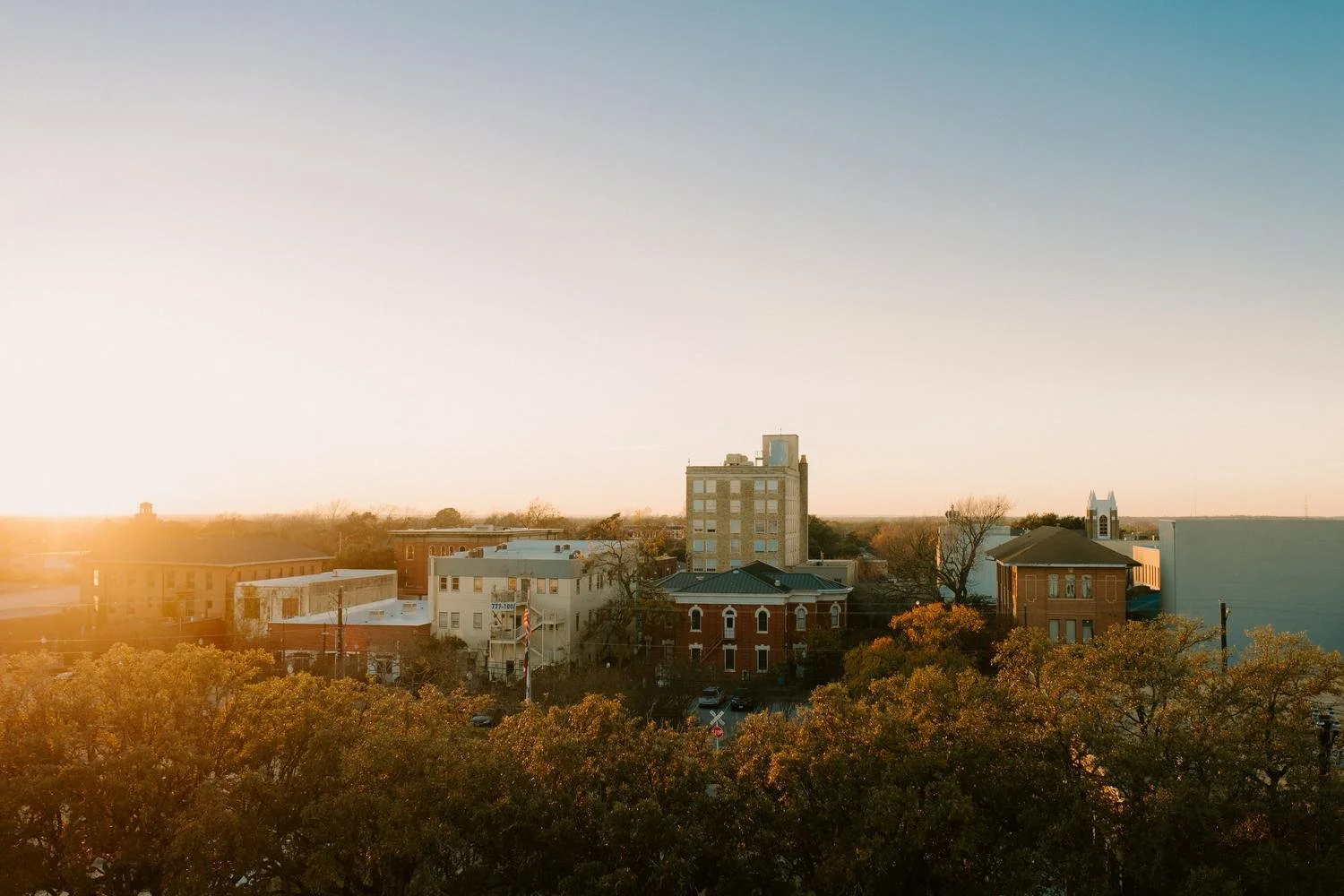 Sunrise over a small downtown area with buildings and trees in autumn colors.