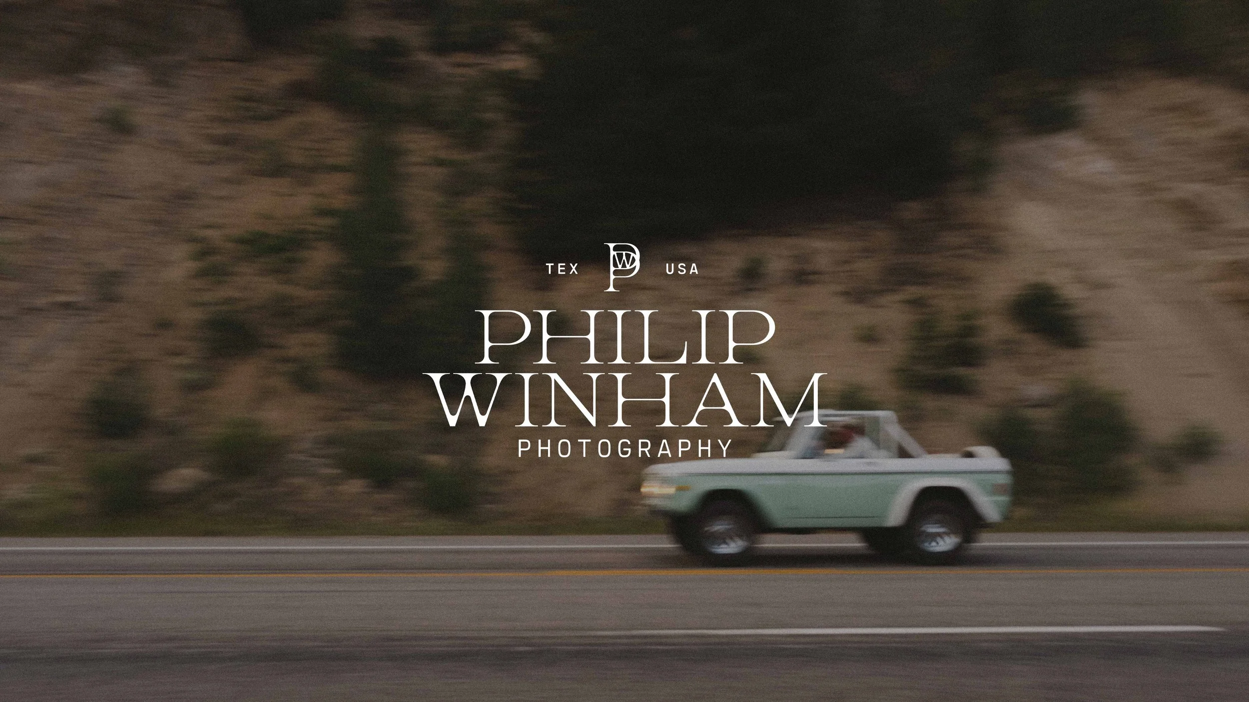 A vintage green pickup truck driving on a highway with a rocky hillside in the background. Text overlay reads 'TEX USA PHILIP WINHAM PHOTOGRAPHY'.