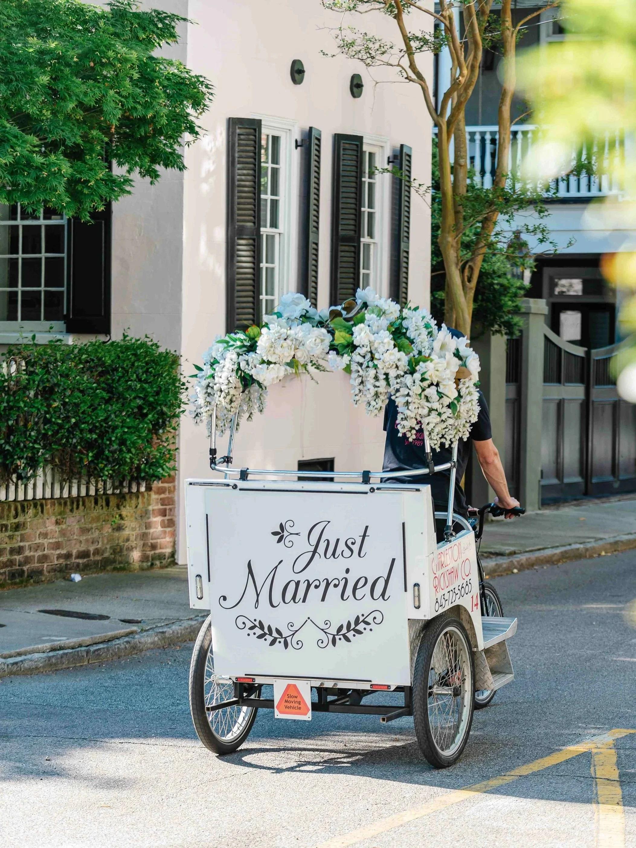 Pedicab with a Just Married sign and white flowers on a downtown Charleston street