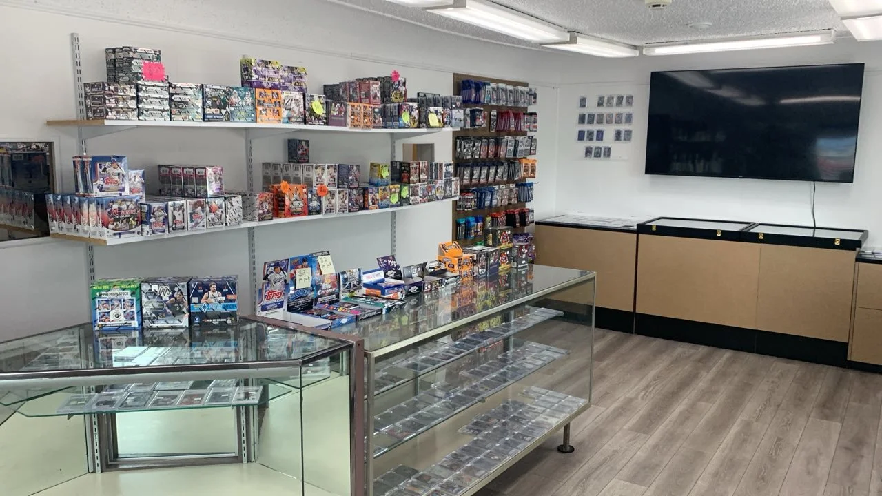picture of interior of sports card and TCG/ Pokemon shop in Saginaw michigan, shows a variety of sealed product and a showcase of singles buying and selling cards implied