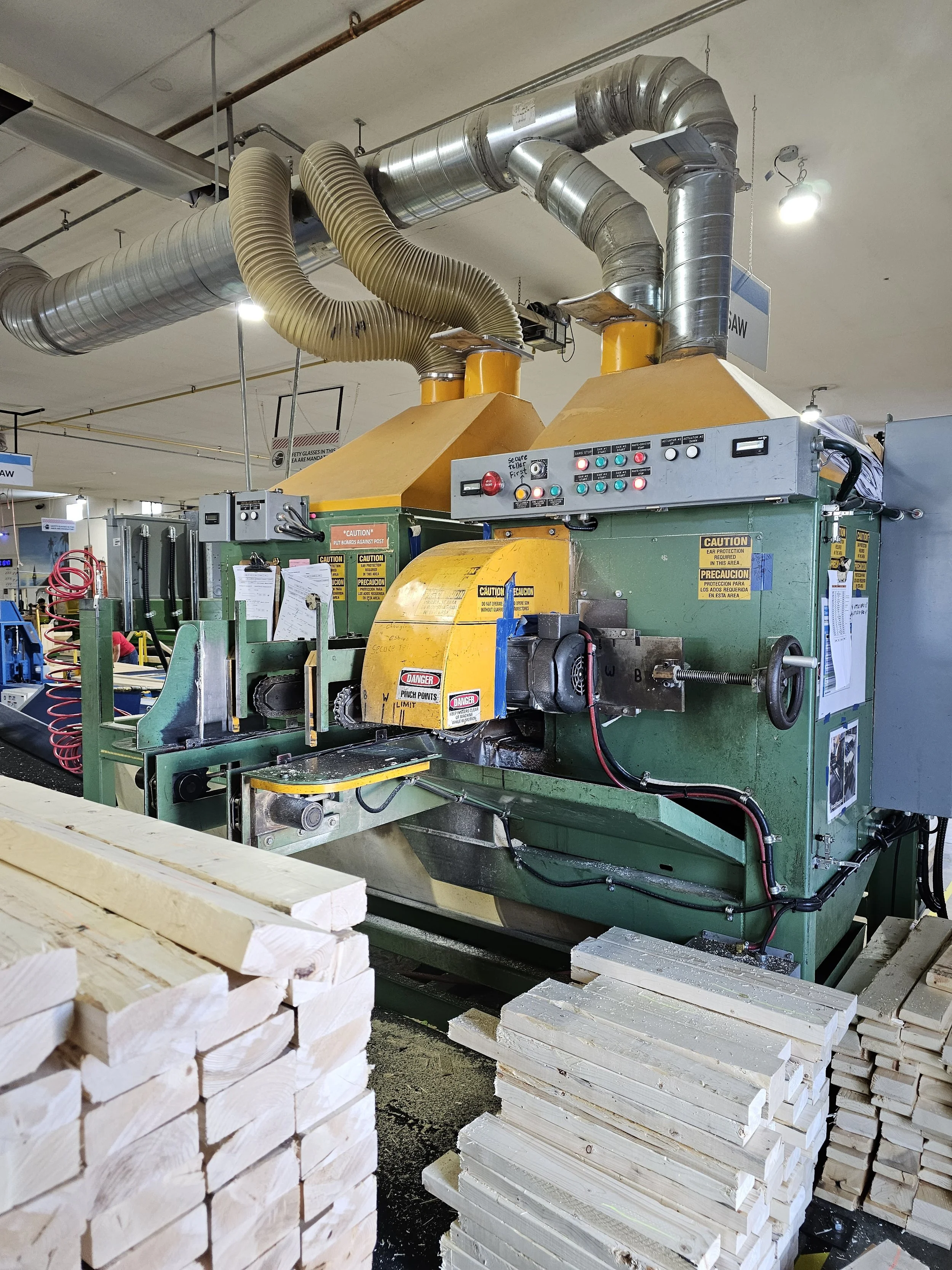 Industrial machine processing stacks of cut wood in a woodworking shop.
