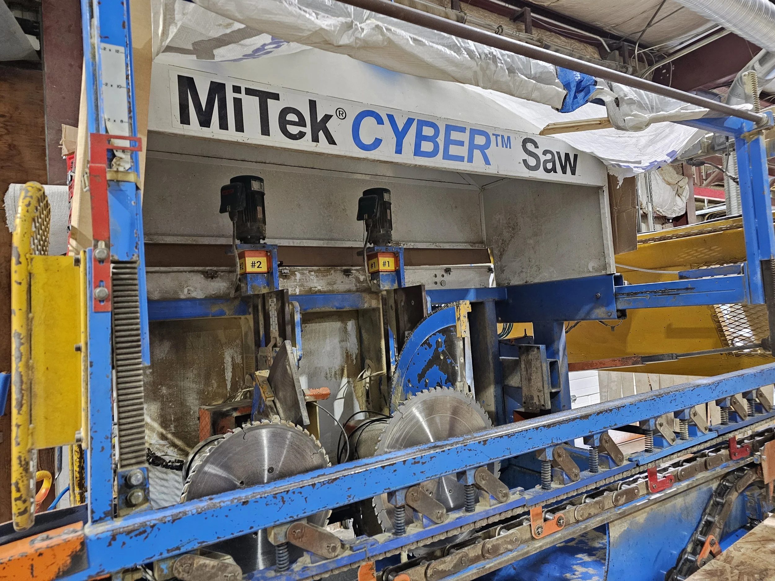 A blue construction saw with large circular blades in a workshop or construction area.