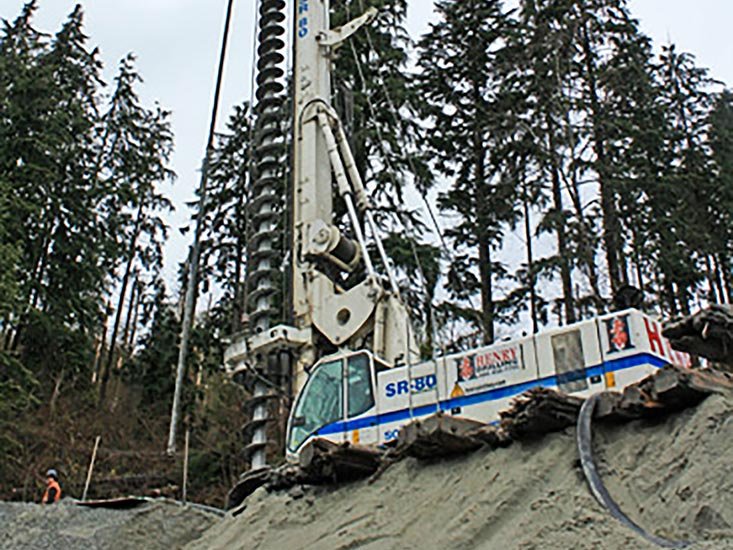 A large drilling machine positioned on a construction site with trees in the background.
