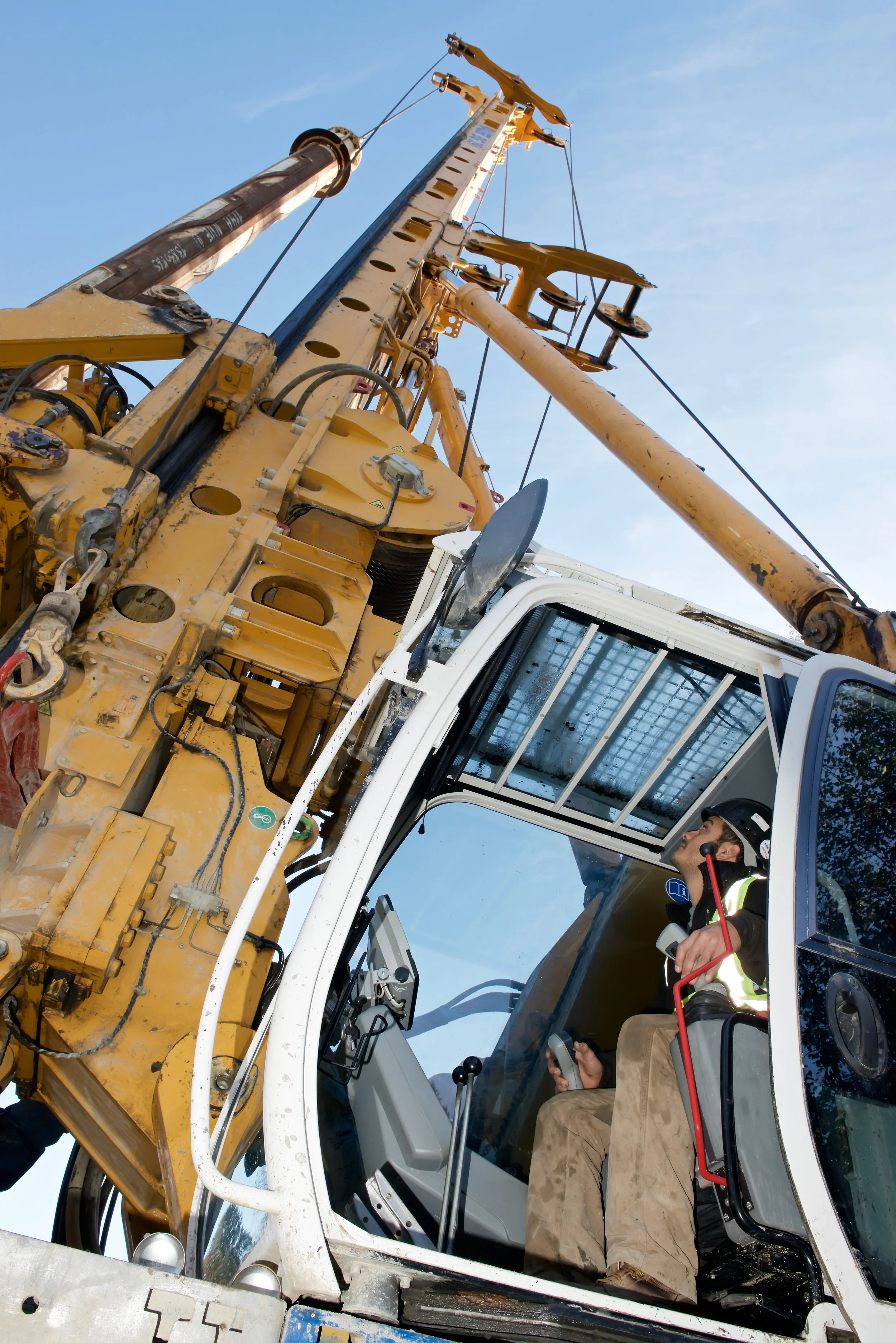 Construction crane viewed from below with a person operating the controls inside the cabin.