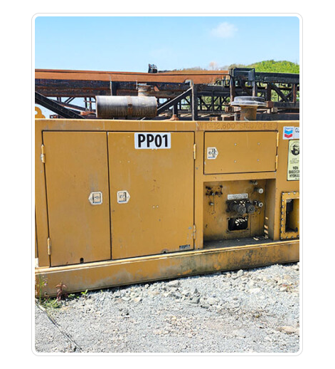 Yellow industrial generator with various controls and panels, labeled PP01, with a gravel ground and clear blue sky background.