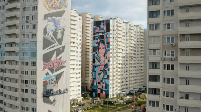 Tall white apartment buildings with two vertical murals