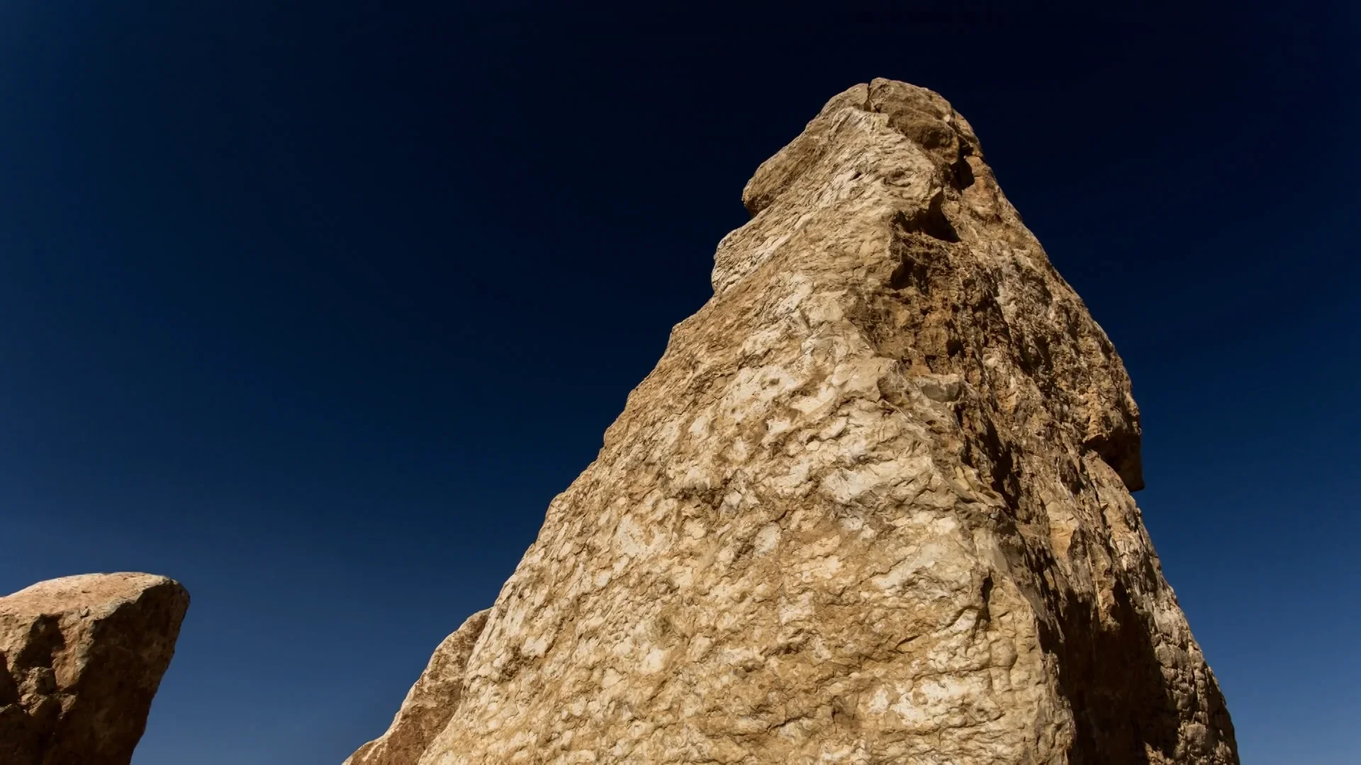 Large pointed rock against a solid blue sky
