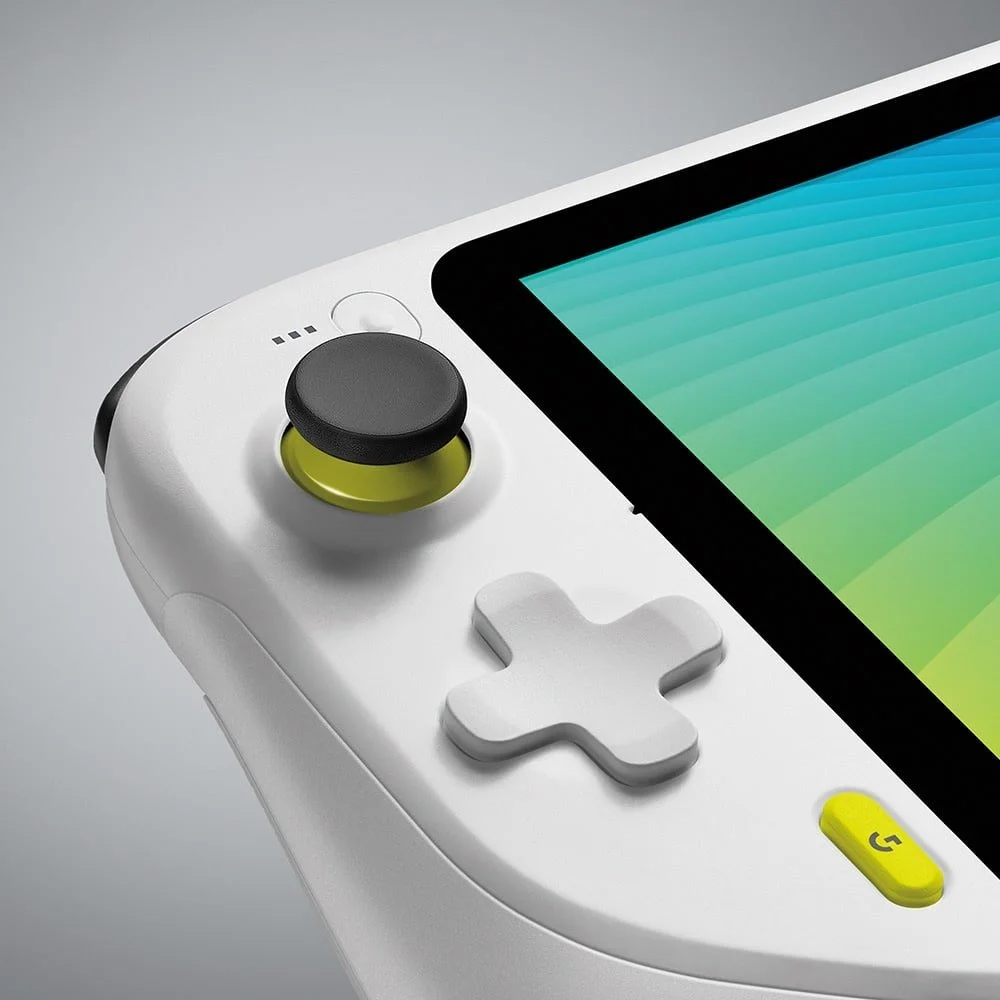 Close-up of a white handheld gaming device with a colorful screen, a black and yellow joystick, a white D-pad, and a yellow G button.