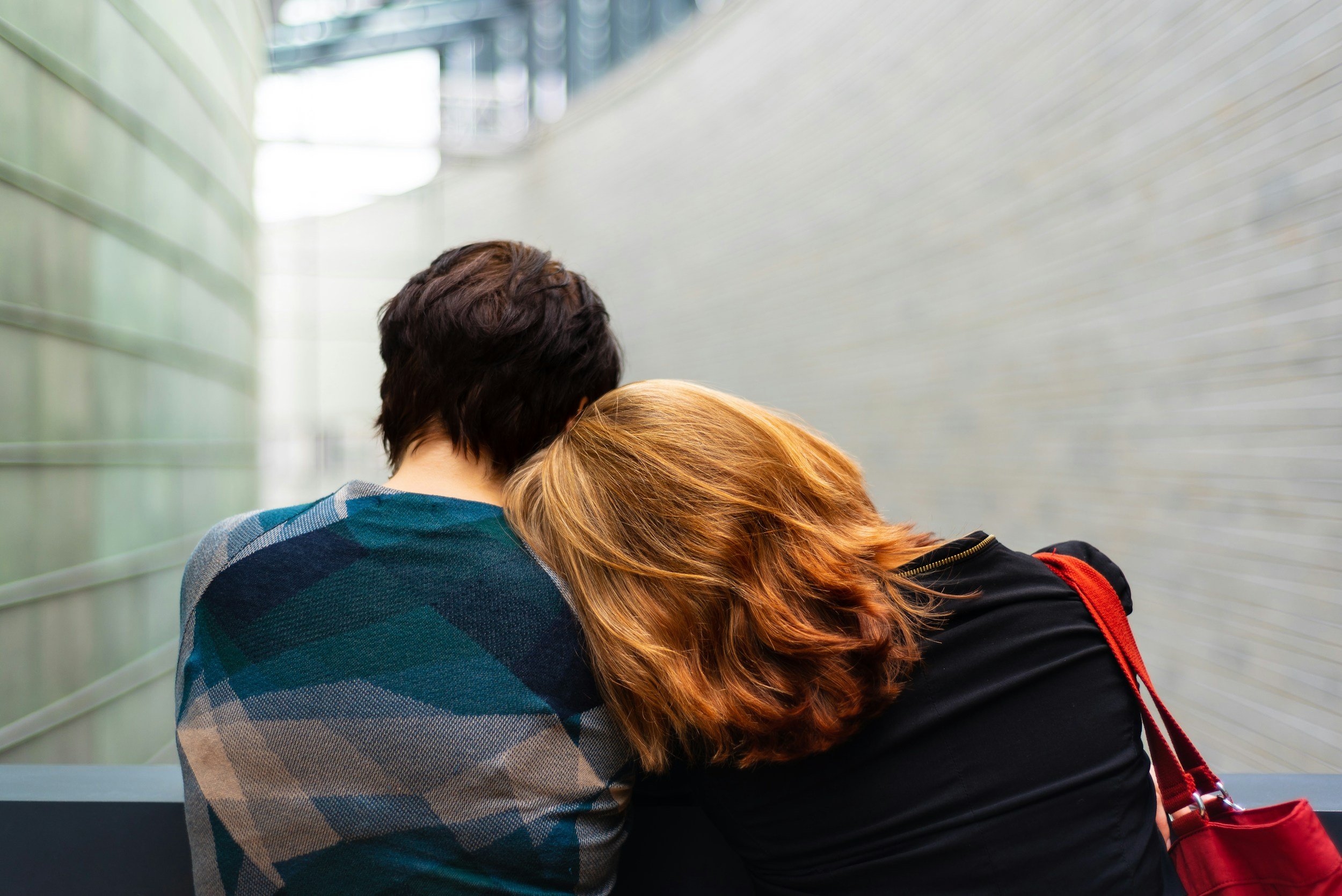 Two individuals leaning on each other representing emotional support, connection, and mental wellness.