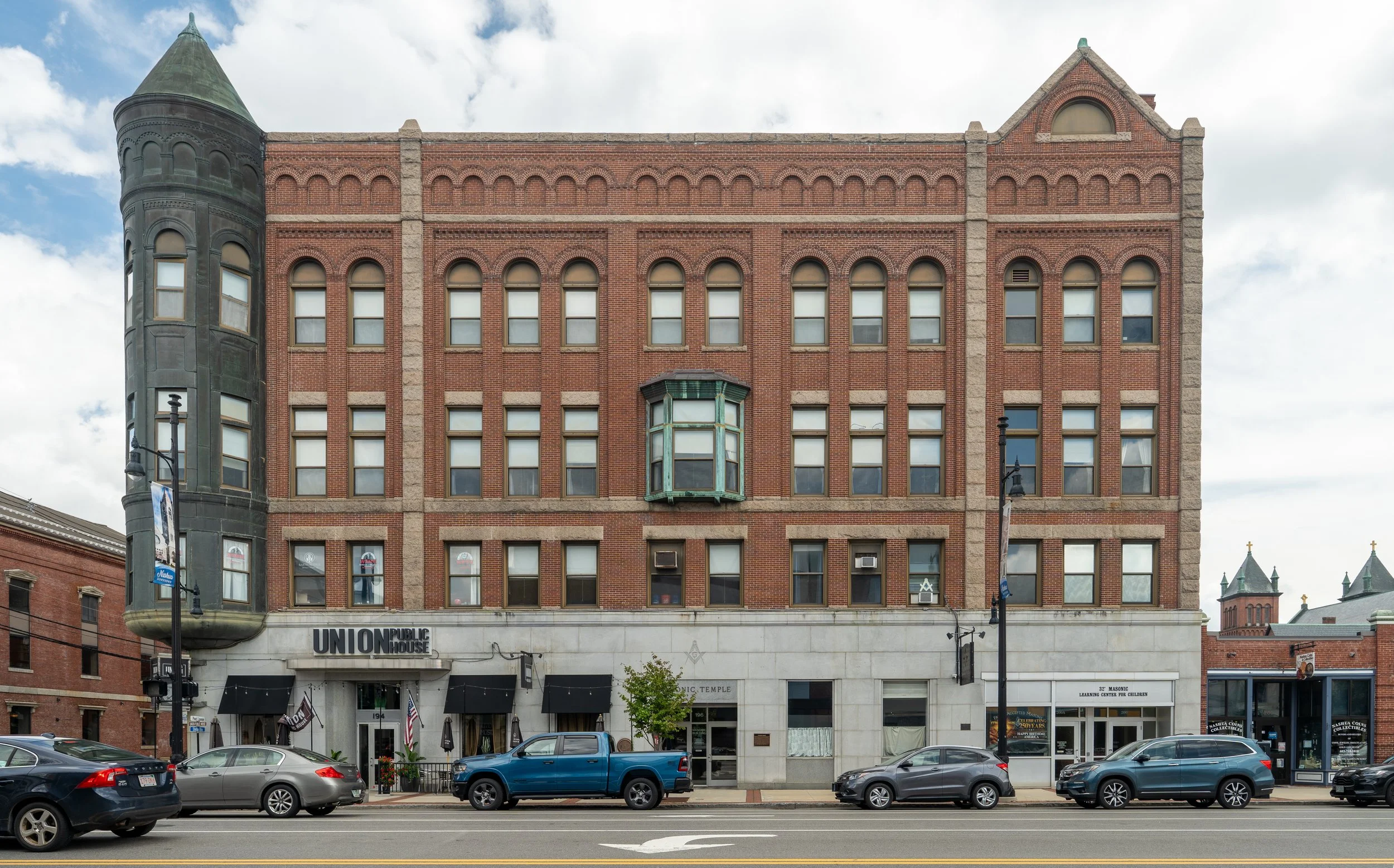 An old brick building with a turret on the left side and several large arched windows, labeled 'Union Public House,' located on a busy city street with parked cars and a few pedestrians.