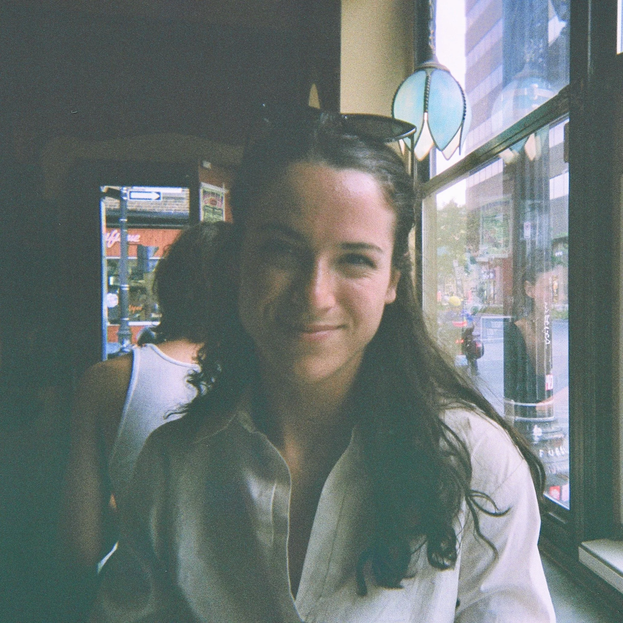 image of a young woman sitting in a busy cafe smiling at camera