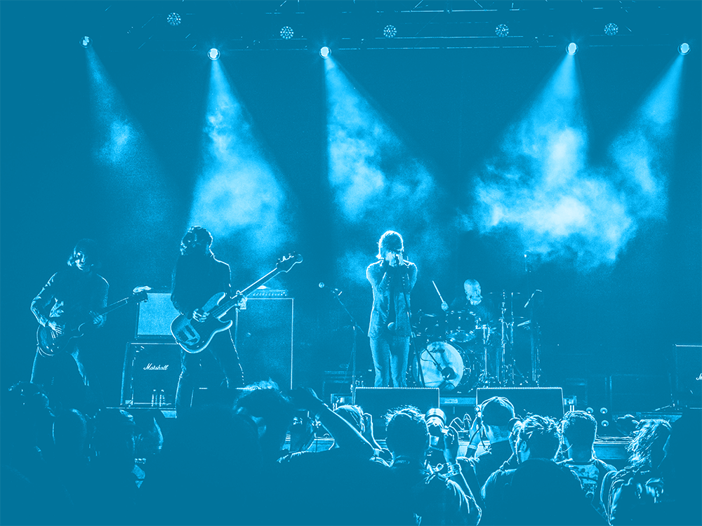 Photo of a concert with blue lights illuminating a band on stage.