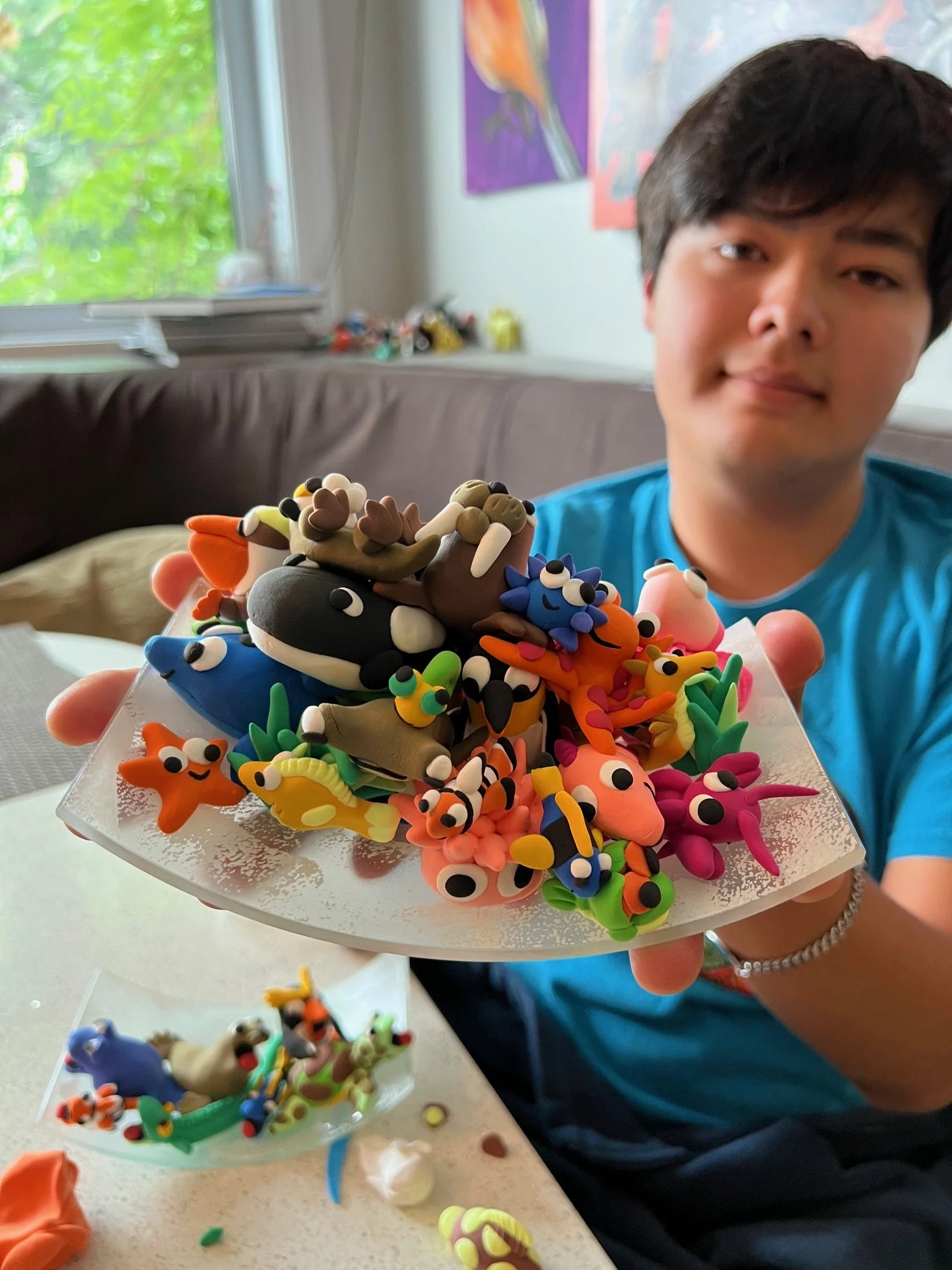 image of a young autistic man holding up a tray of clay sculptures