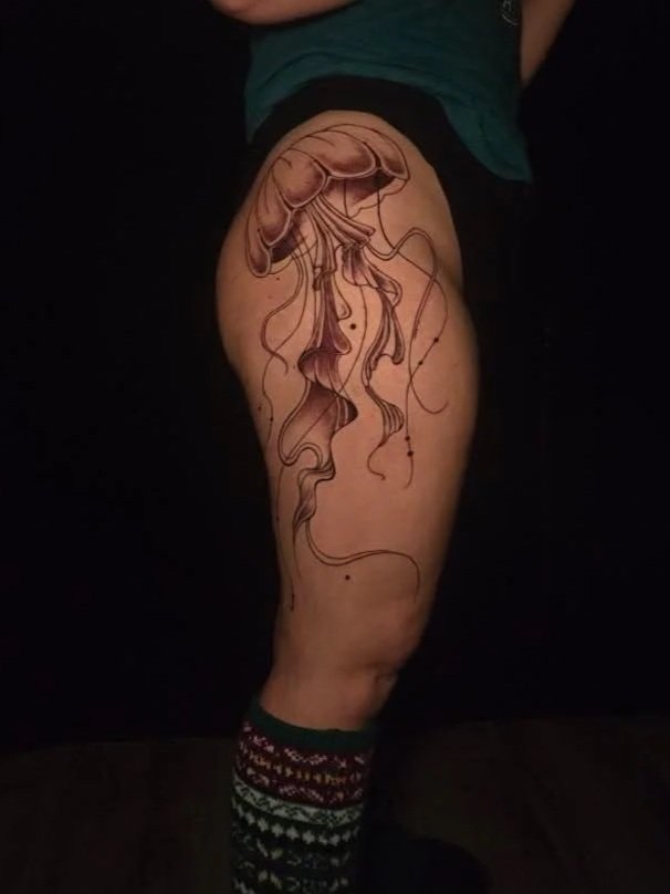 Tattoo of a jellyfish on a person's upper thigh.