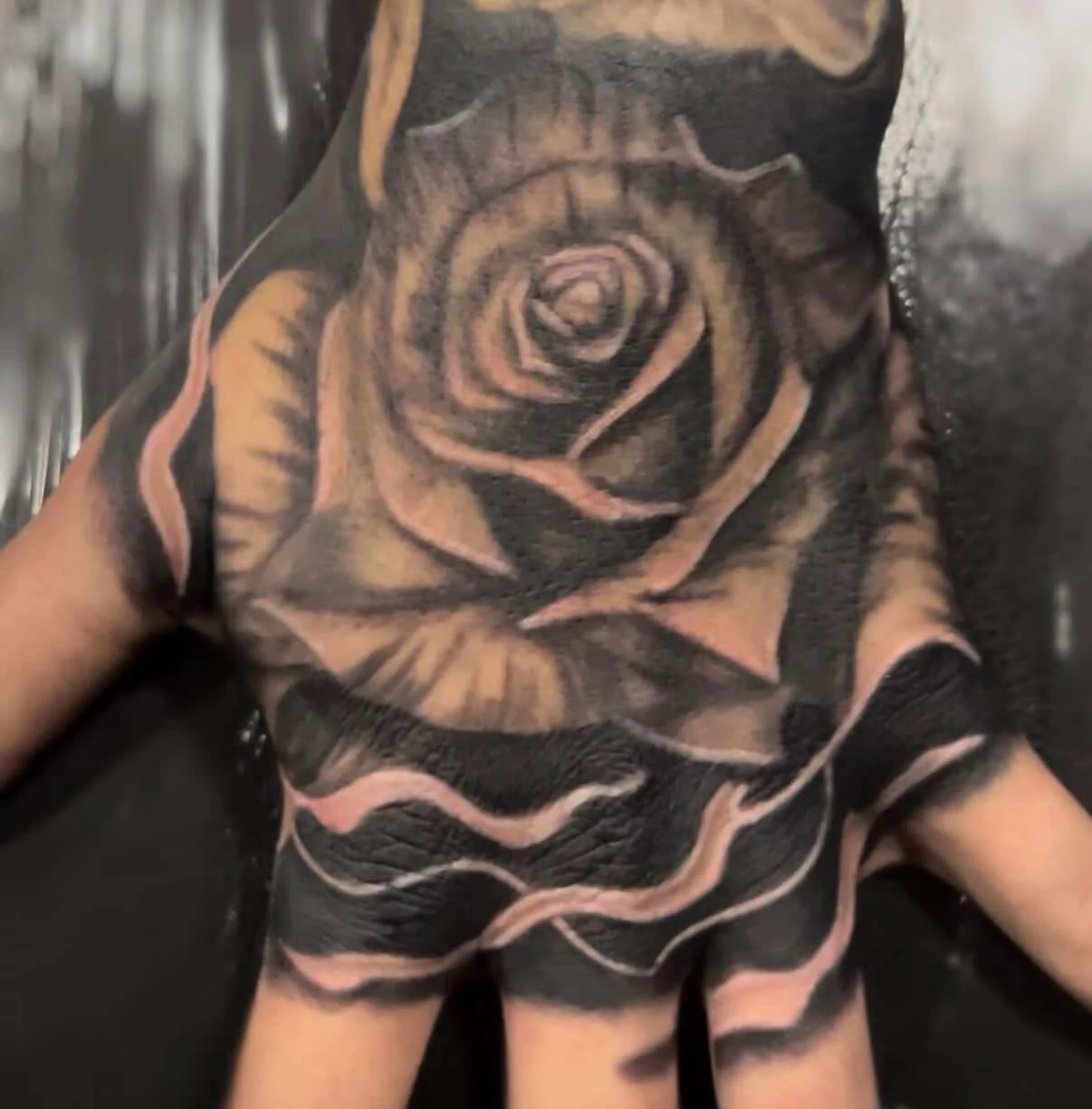 Close-up of a person's chest with a large black and beige rose tattoo.