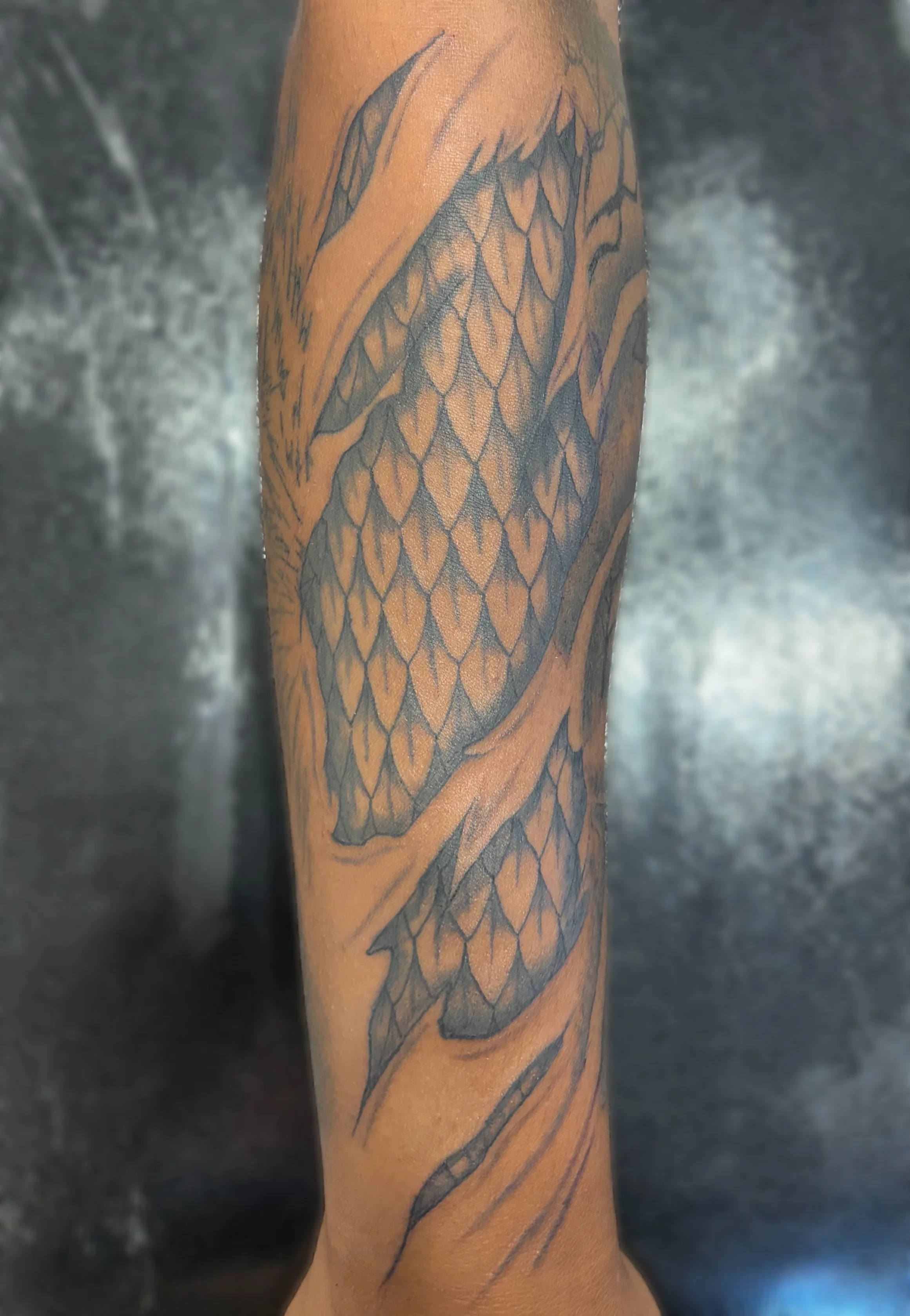 Tattoo of a dragon on a person's arm with detailed scales and wings.