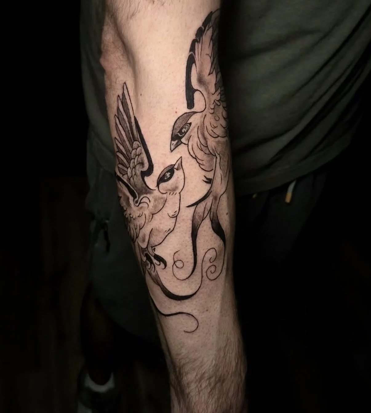 Tattoo of a stylized griffin or mythical creature on a person's arm.
