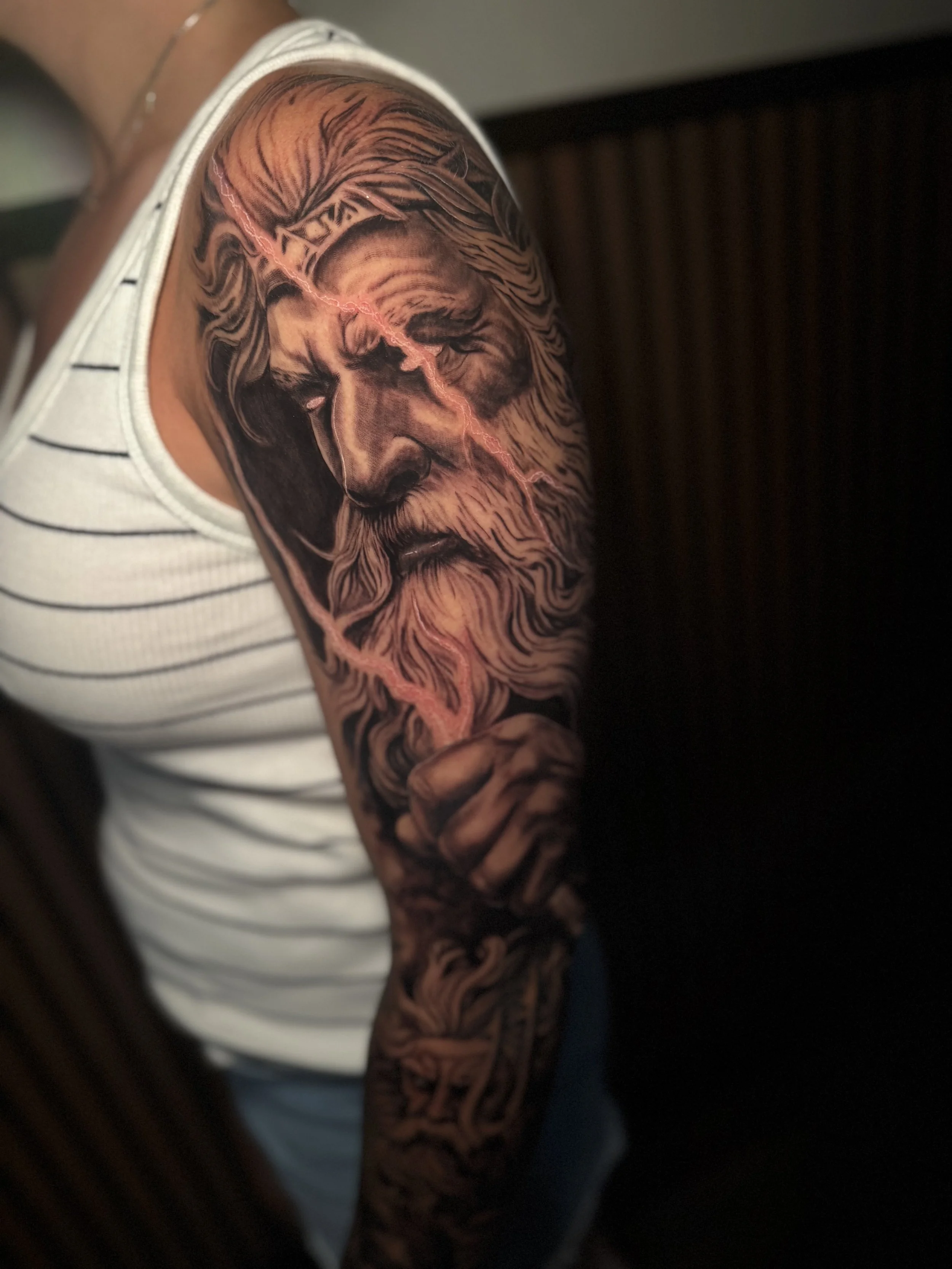 Close-up of a person's arm with a large, detailed black and gray lion tattoo.