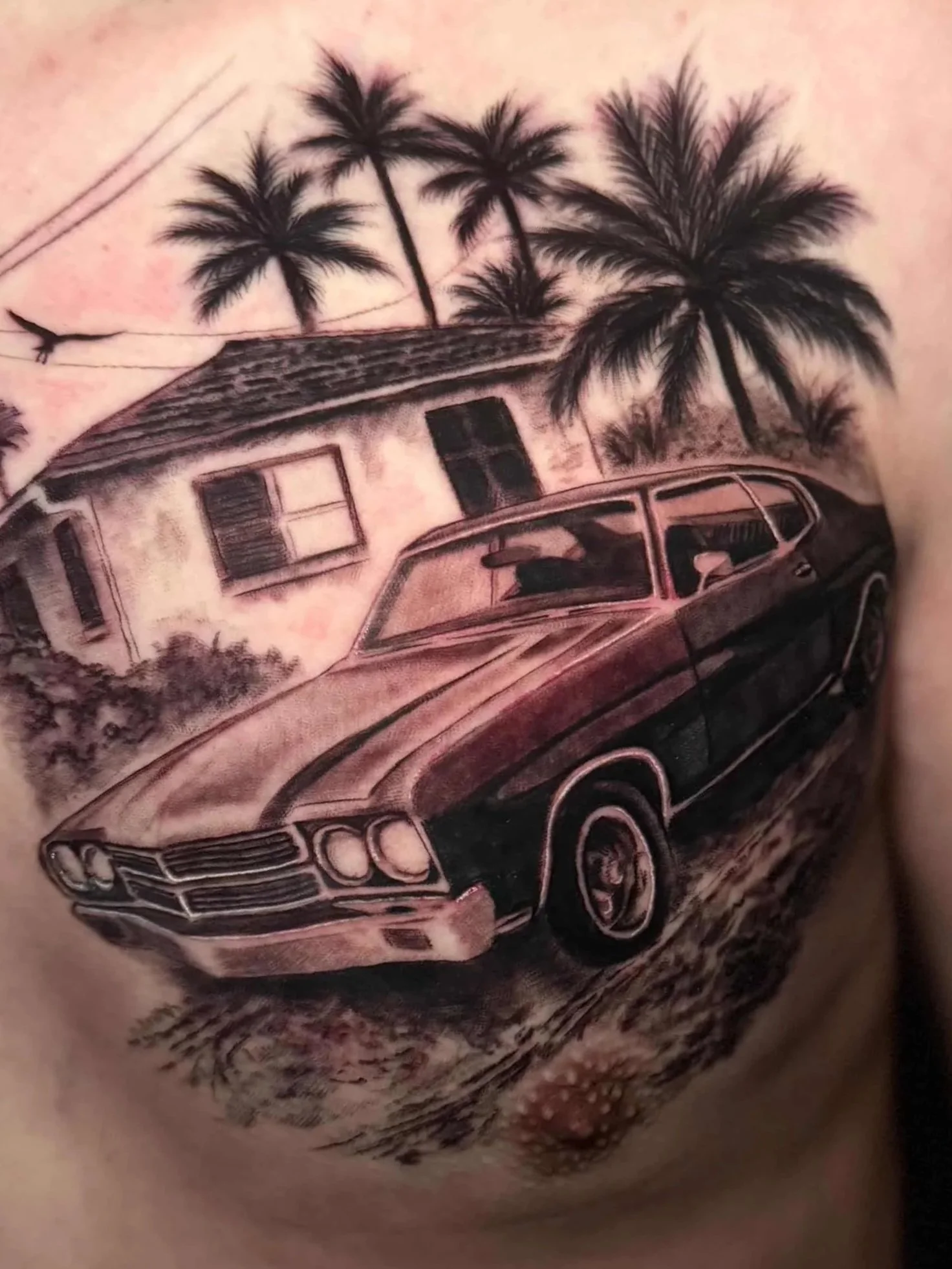 Tattoo of a vintage car with palm trees and a house in the background.