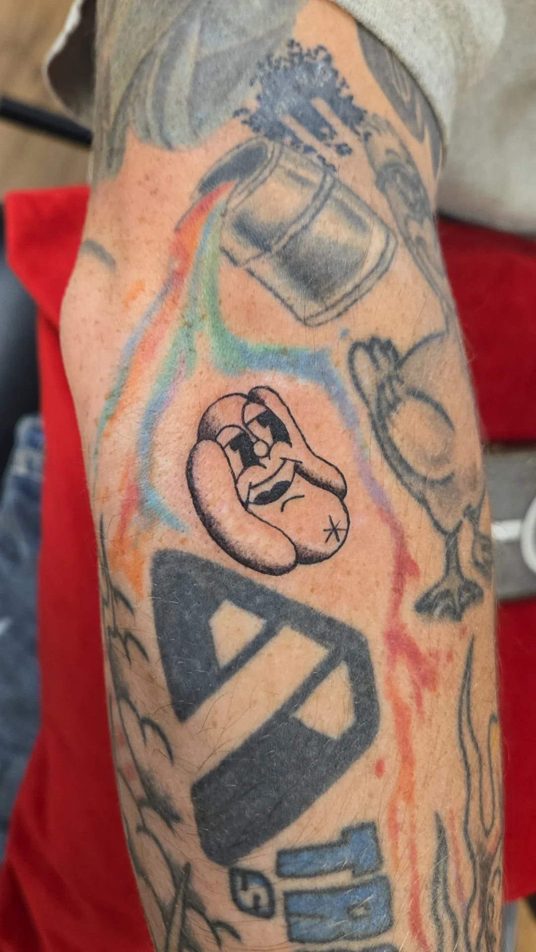 Tattoo of a cartoon-style telephone with a worried facial expression on the person's arm.