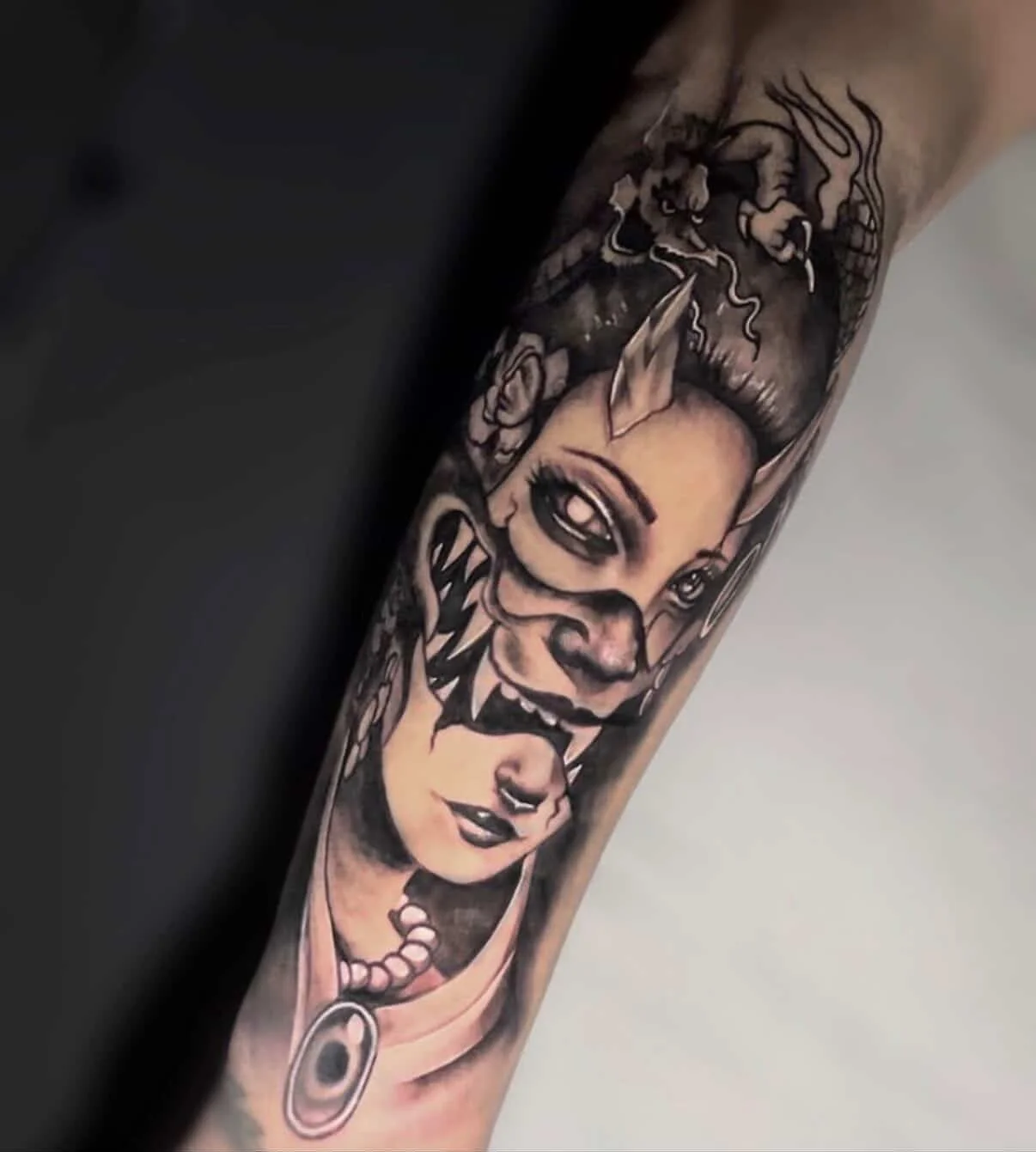 Black and gray tattoo featuring a woman with makeup, a tattooed face, and a lion at the top.