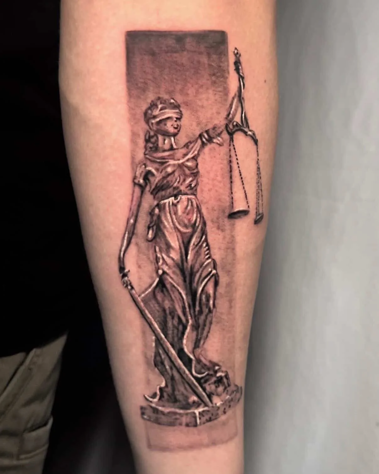 Tattoo of Lady Justice holding scales and sword.