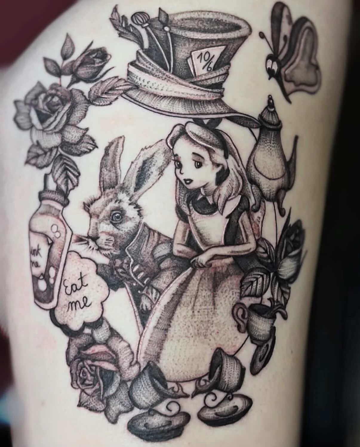Tattoo illustration of Alice from Alice in Wonderland with a rabbit, a butterfly, a tea cup, roses, a bottle labeled 'Eat me,' a top hat with a '10/6' card, and various decorative elements.