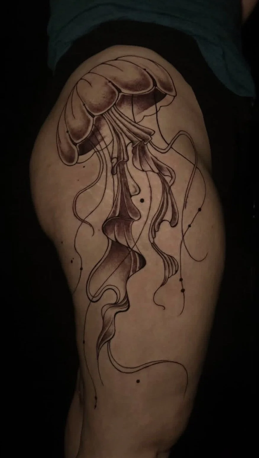 Tattoo of a jellyfish on person's thigh with flowing lines and abstract elements.