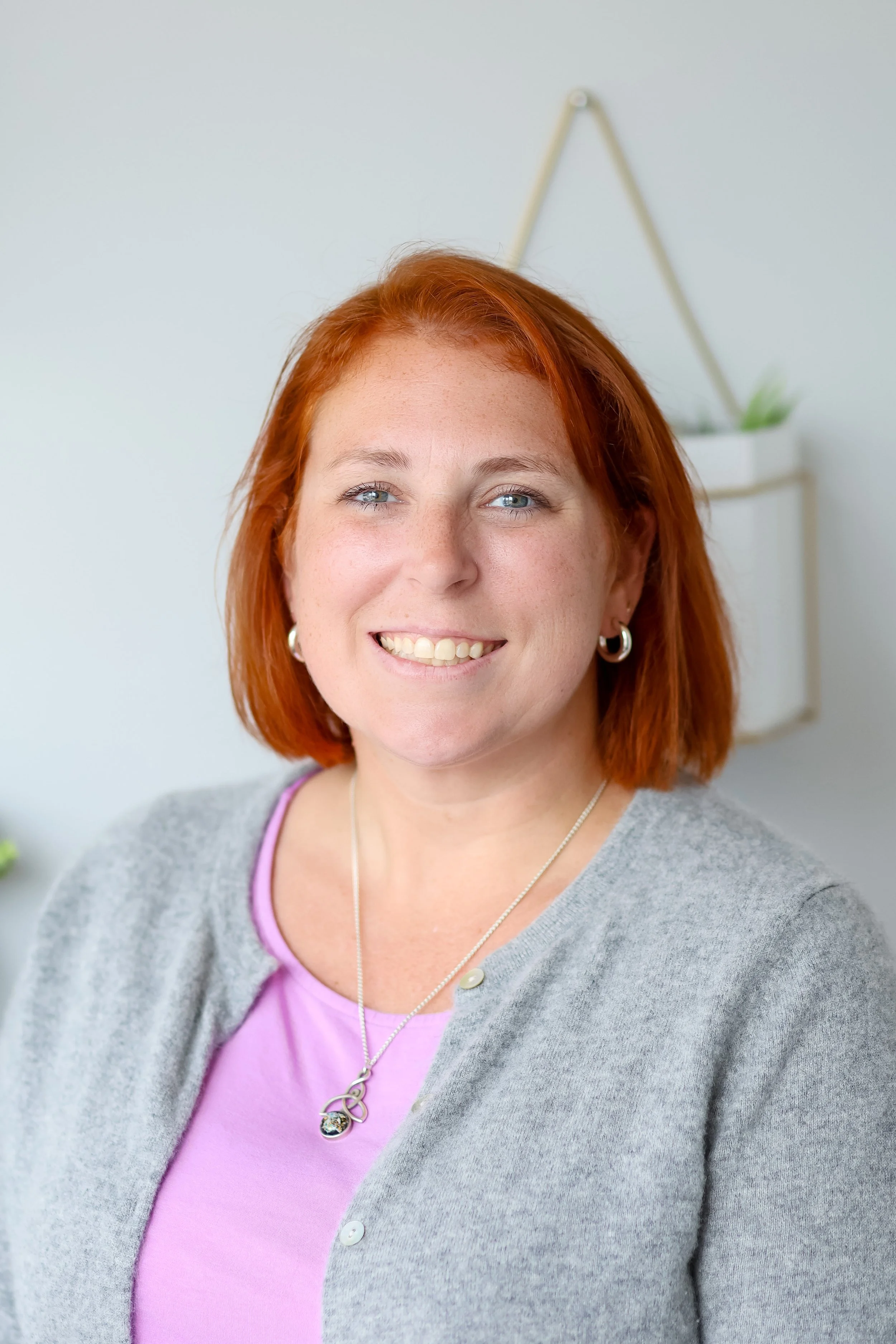 Sarah Schufreider, LCSW, smiling in a grey cardigan — postpartum depression therapist serving Illinois and Chicago