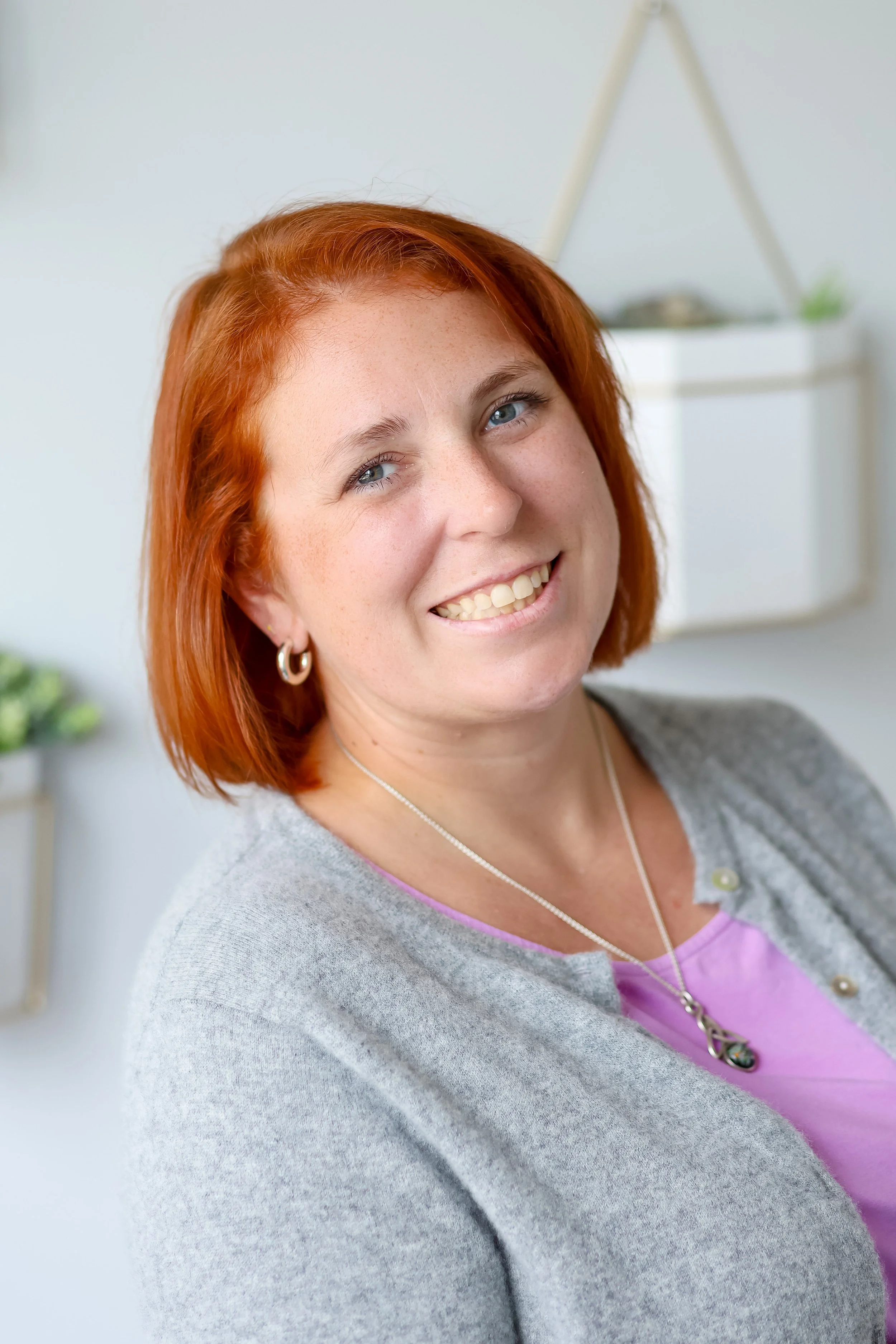sarah schufreider lcsw menopause therapist chicago smiling in office wearing grey sweater and purple dress
