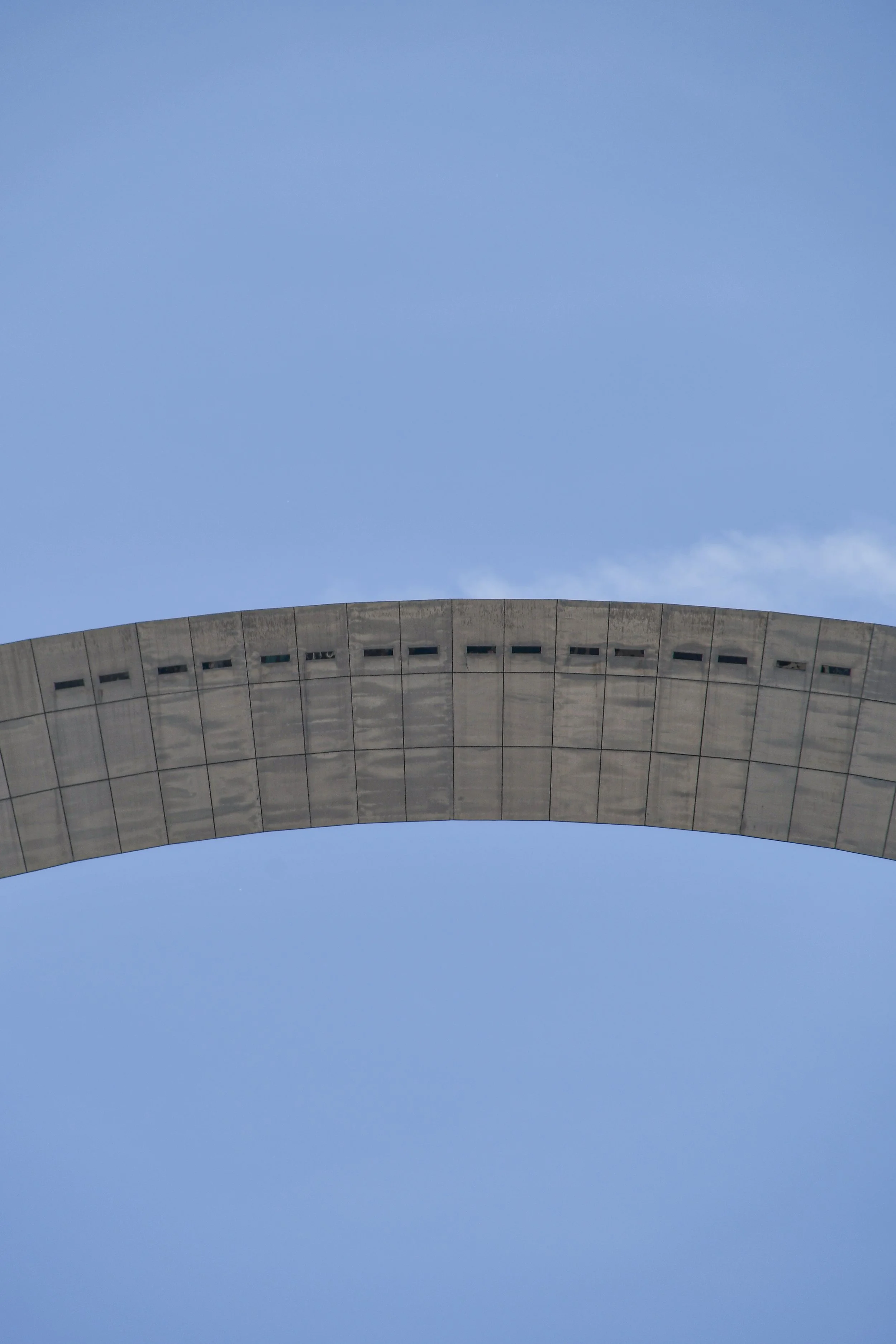 Close-up of a curved building with a concrete facade against a bright blue sky.