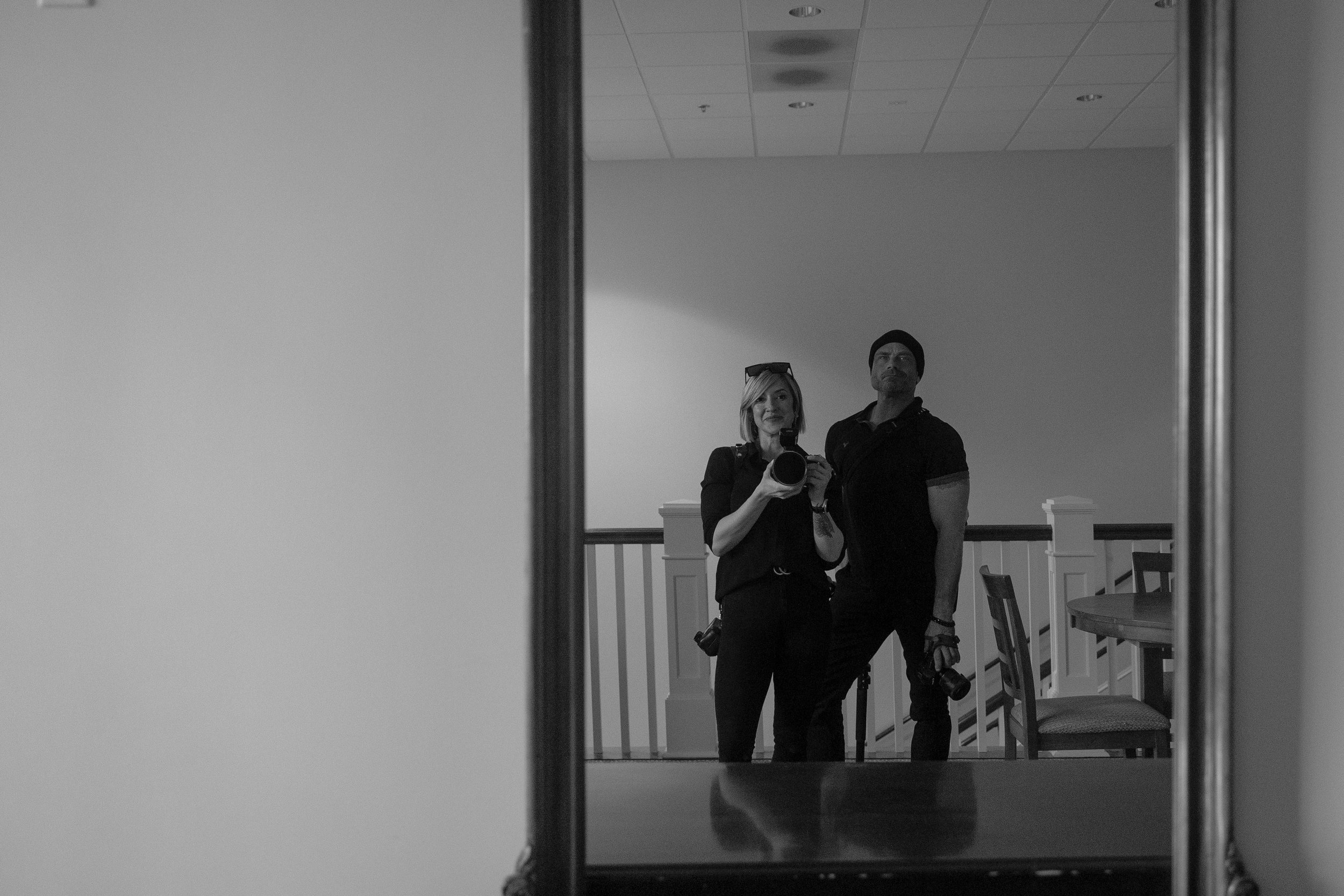 Mirror portrait of Aperture & Atlas photographers Stuart and Autumn capturing a behind-the-scenes moment inside a modern interior.