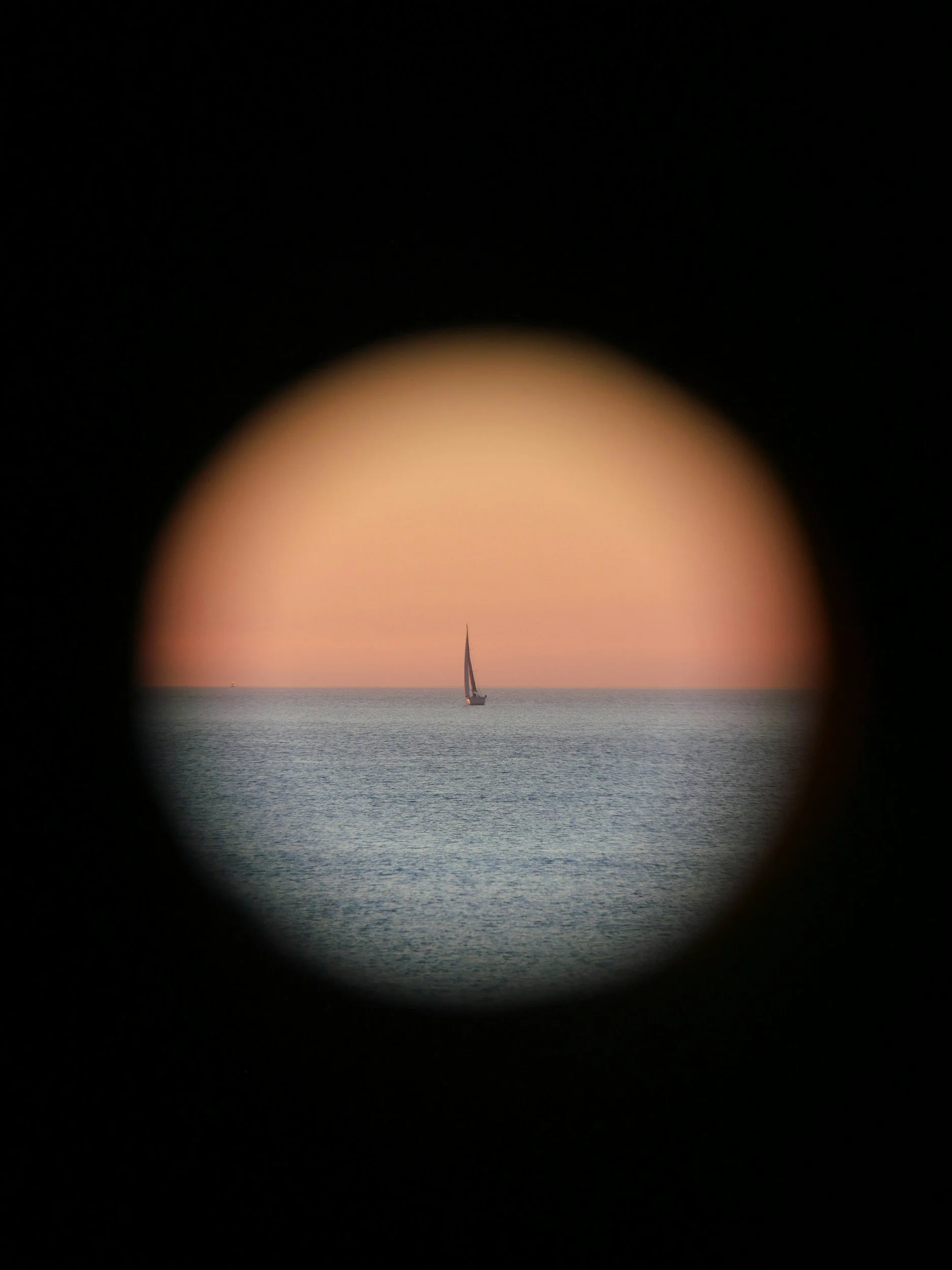 Velero en el mar visto a través de un visor o lente, con fondo de cielo y agua.