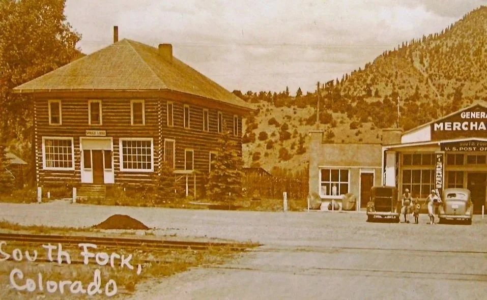 Historical black-and-white photo of a small town in South Fork, Colorado, showing the historic Spruce Lodge in its early days.