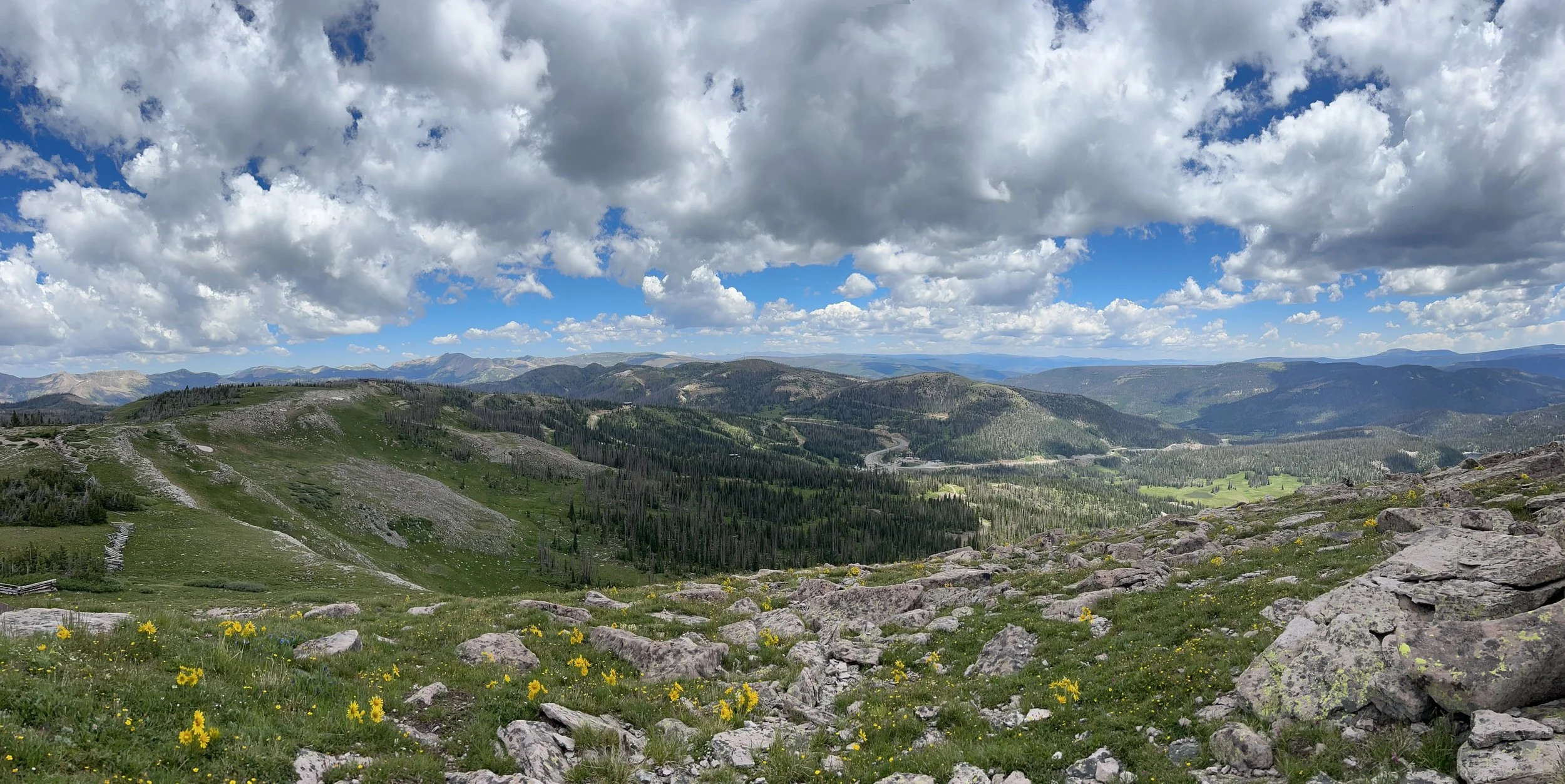 Scenic view of a mountainous landscape with green valleys, rocky areas, and a partly cloudy sky.