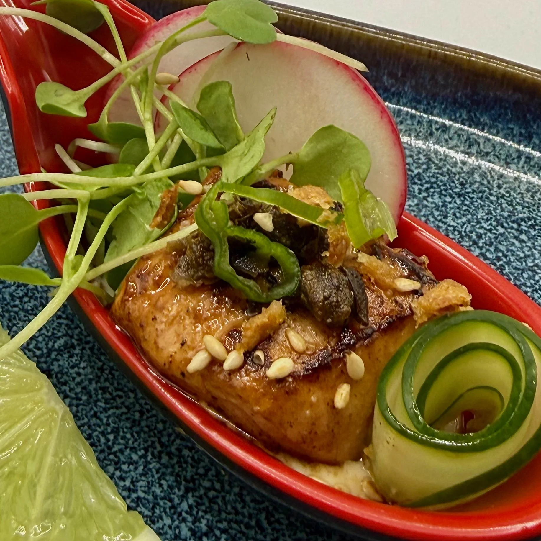 A tender medallion of pan-seared salmon, finished with a rich soy glaze and set over a velvety garlic aioli. Accompanied by a precision cucumber ribbon, toasted sesame, and crispy garlic.