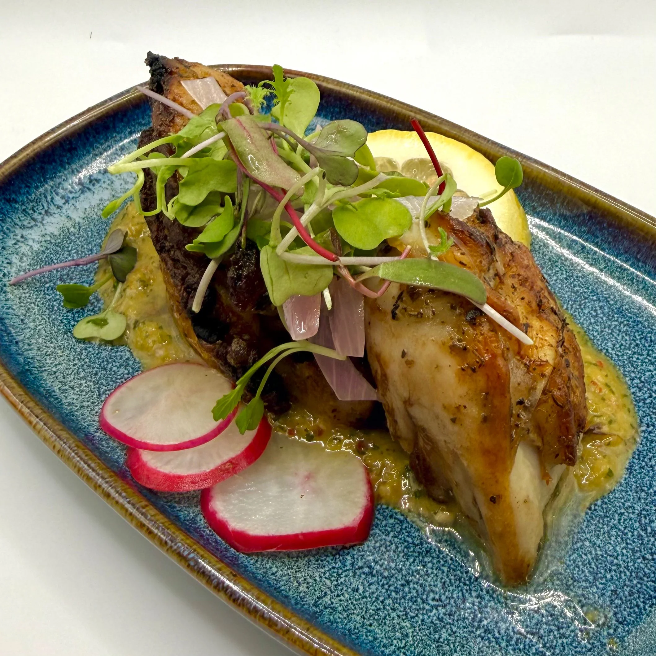 A succulent, bone-in tasting portion of herb-crusted chicken, served over a vibrant, small-batch chimichurri. Garnished with precision-shaved radish, pickled shallots, and fresh micro-greens.