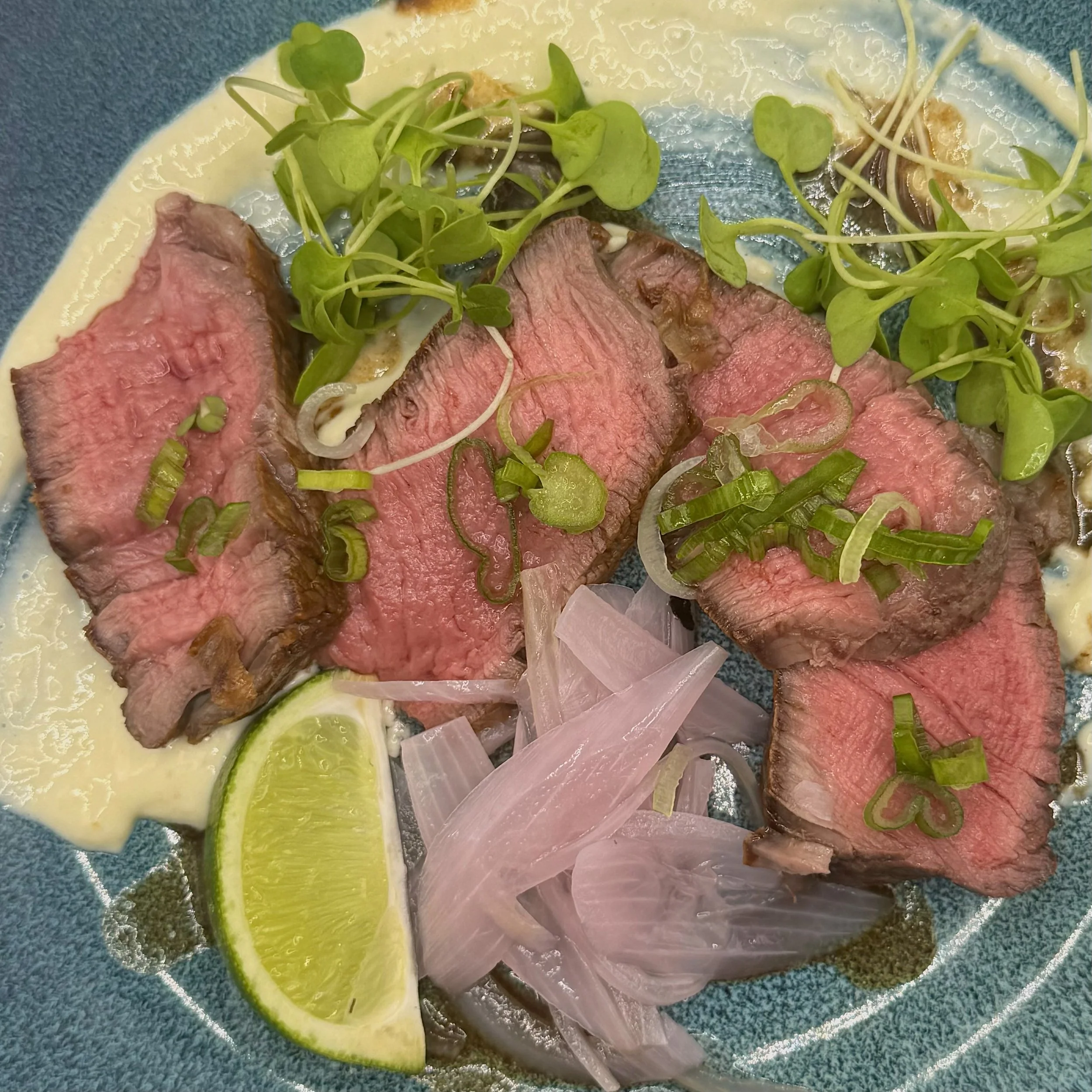 Pan-seared Filet Mignon, cooked to a perfect medium rare and fanned over a velvety garlic-horseradish aioli. Topped with vibrant micro-greens and pickled shallots for a savory, sophisticated bite that melts on the palate.