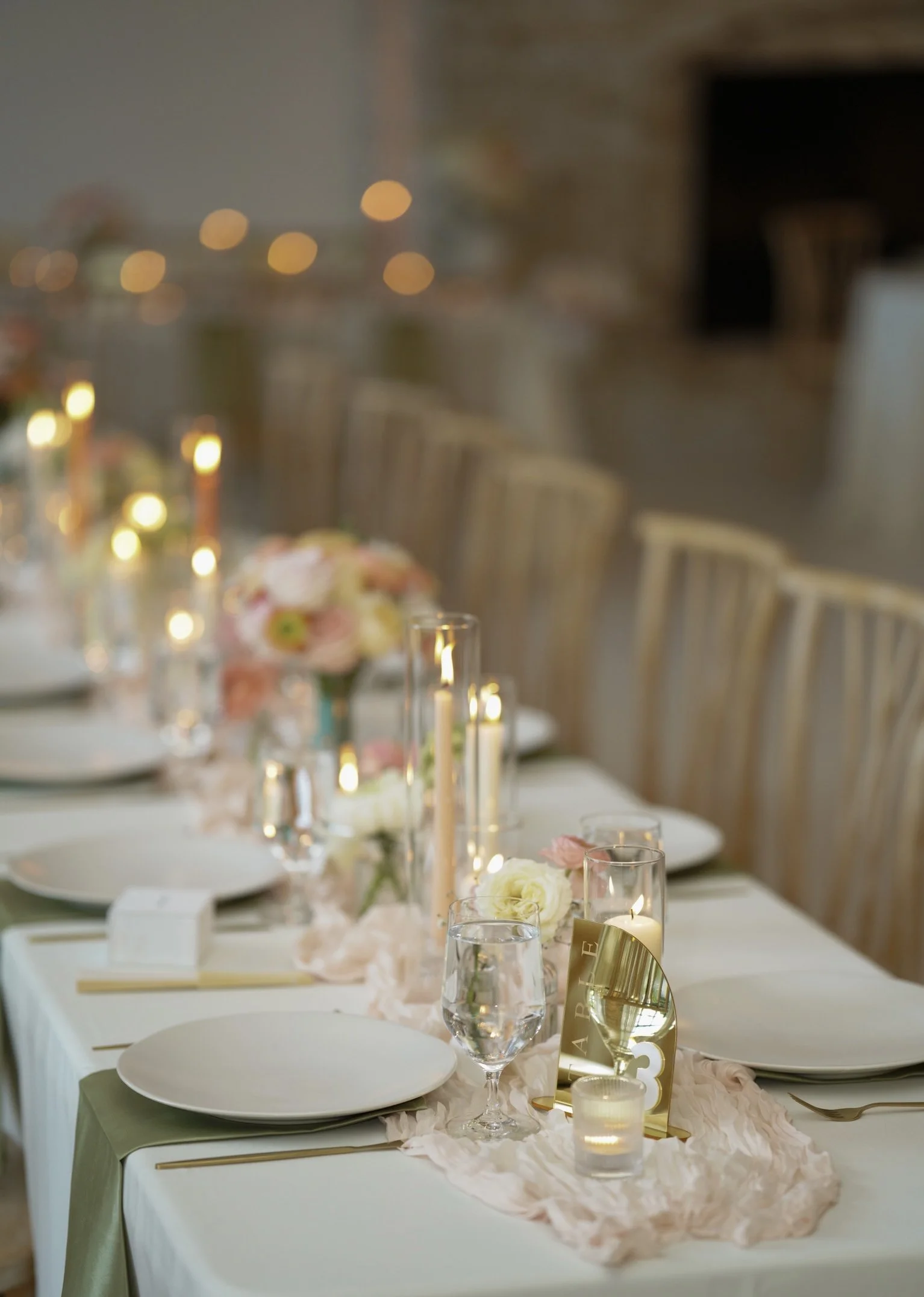 Wedding reception table decorated with flowers, candles, and tableware, with chairs arranged around it.