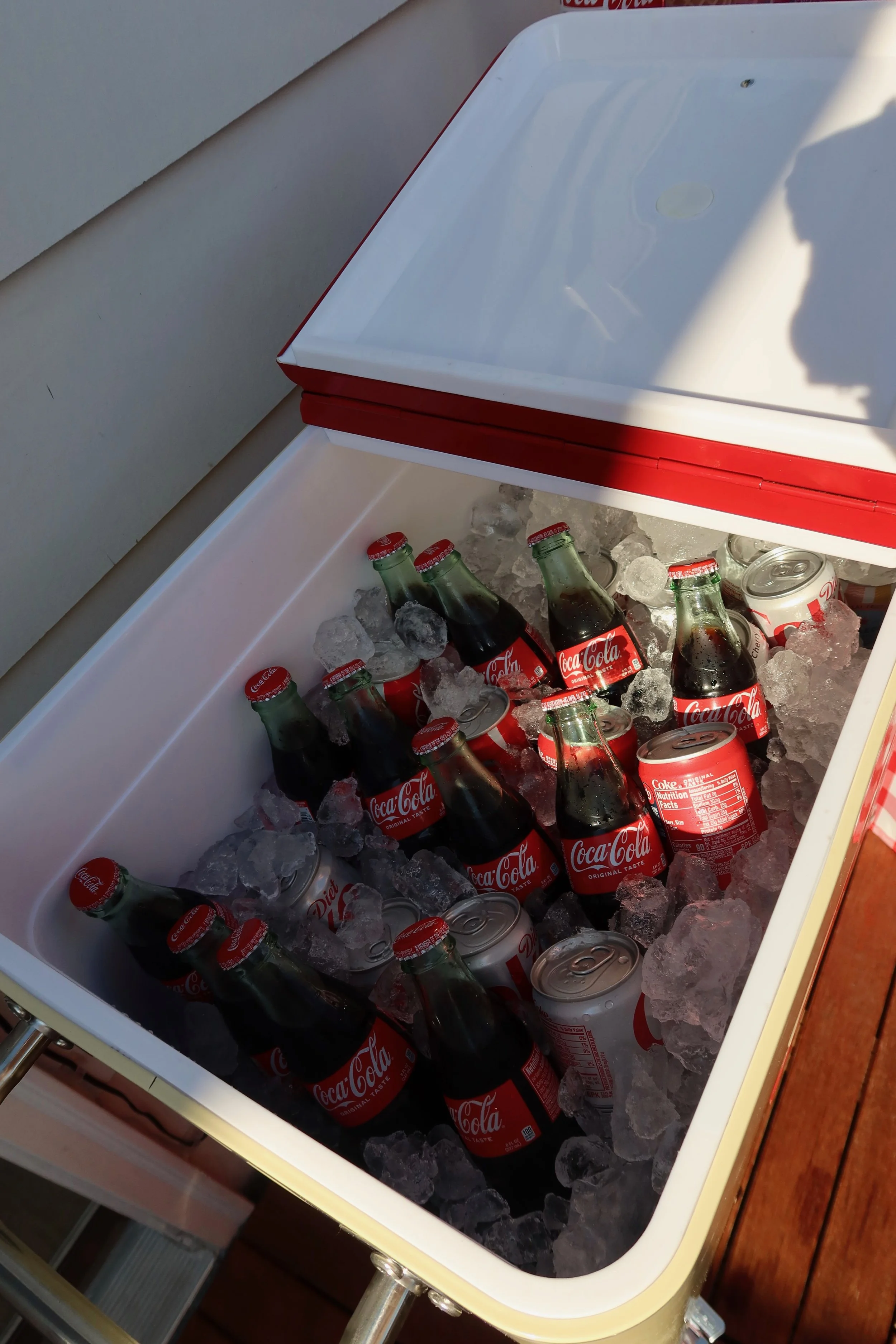 A cooler filled with ice containing several bottles of Coca-Cola and cans of Diet Coke.