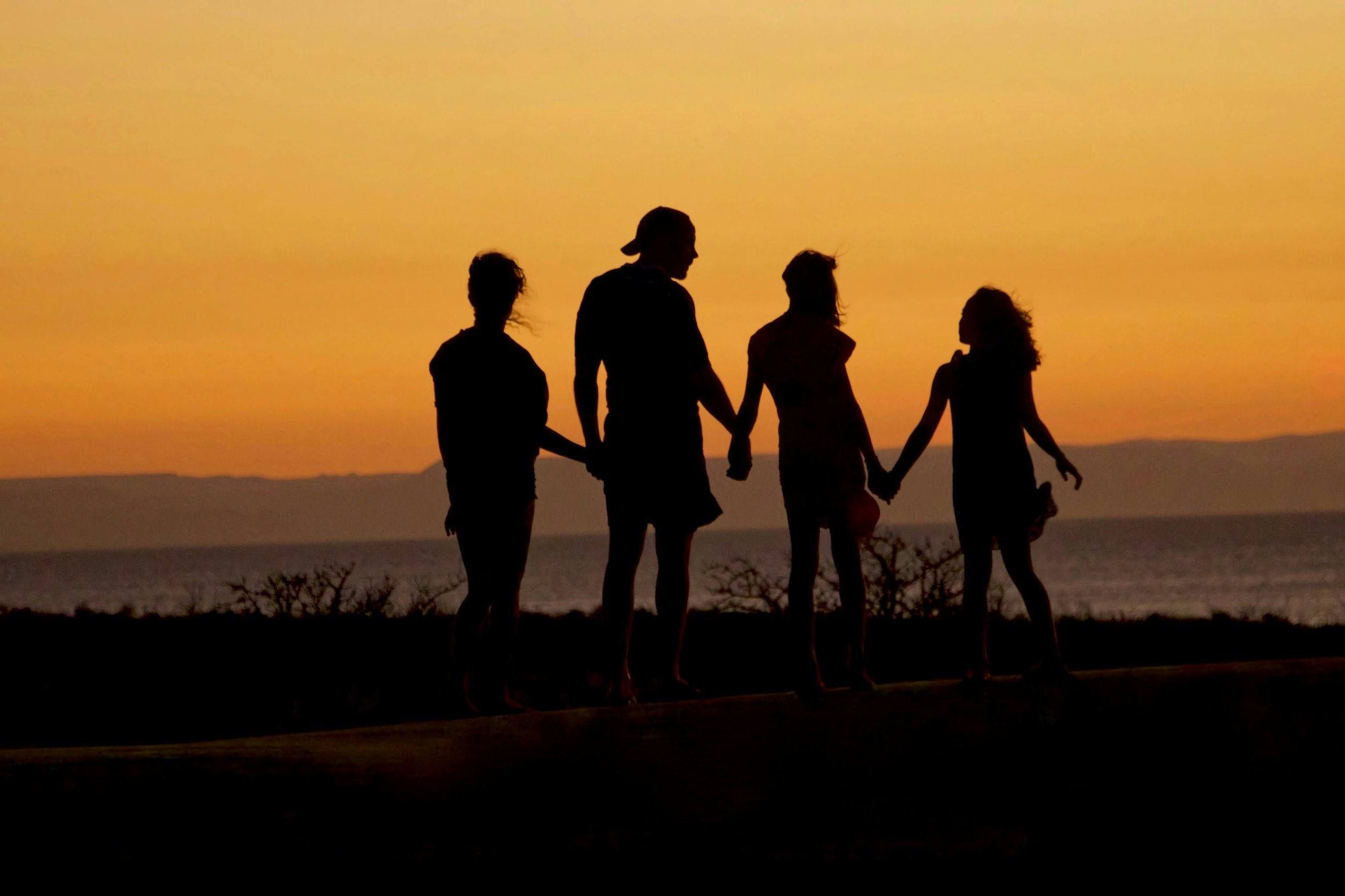 Family standing together, holding hands during sunset