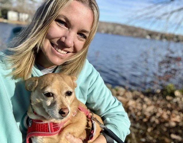 Woman pet caregiver holding a small cute light brown dog.