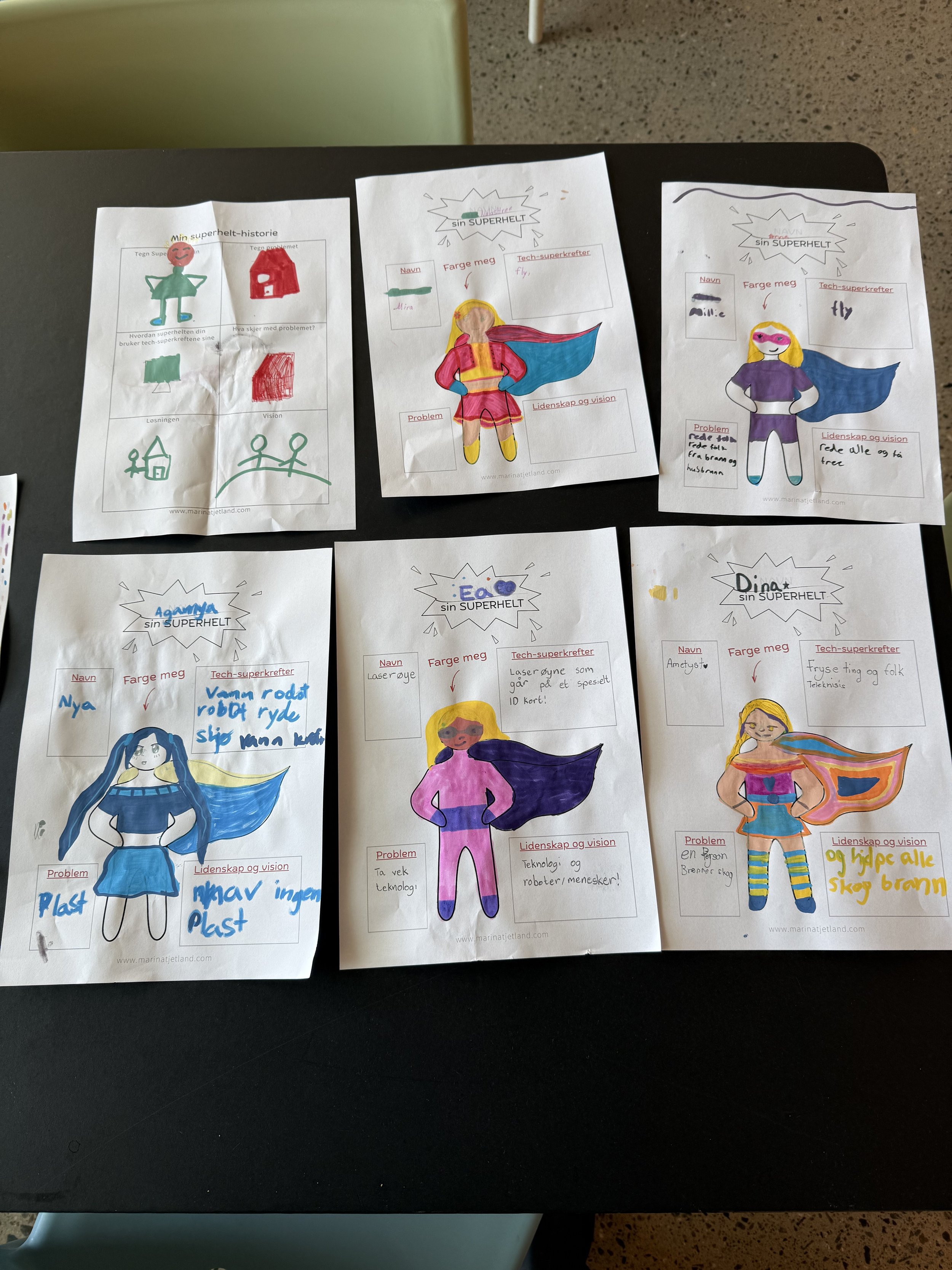 Colorful drawings of girls dressed as superheroes on sheets of paper, accompanied by Norwegian handwritten notes and descriptions.