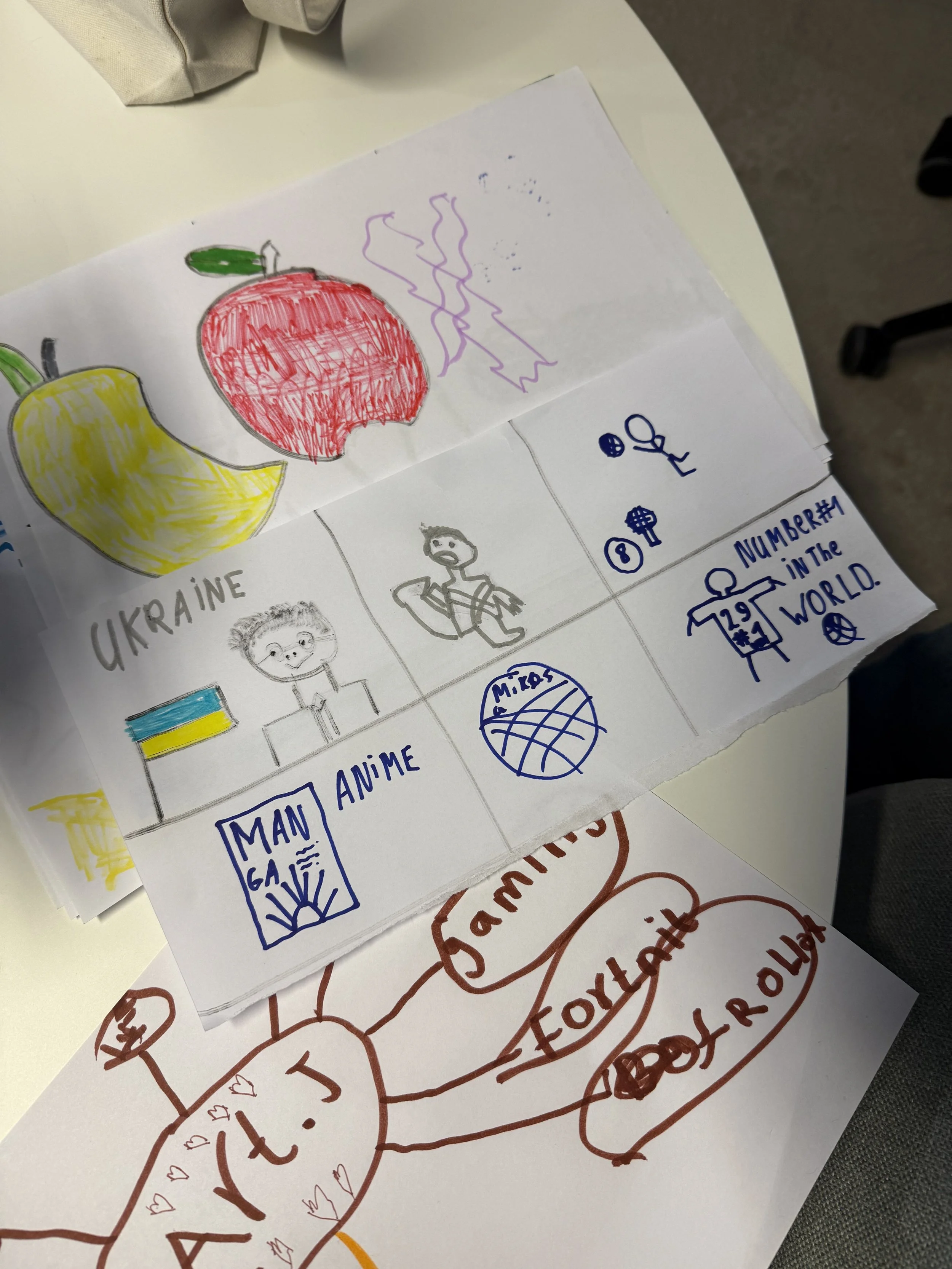 Colorful drawing of the Ukrainian flag with a yellow and blue horizontal stripe, a red apple, and a yellow bell pepper, with hand-drawn text and illustrations on a sheet of paper.