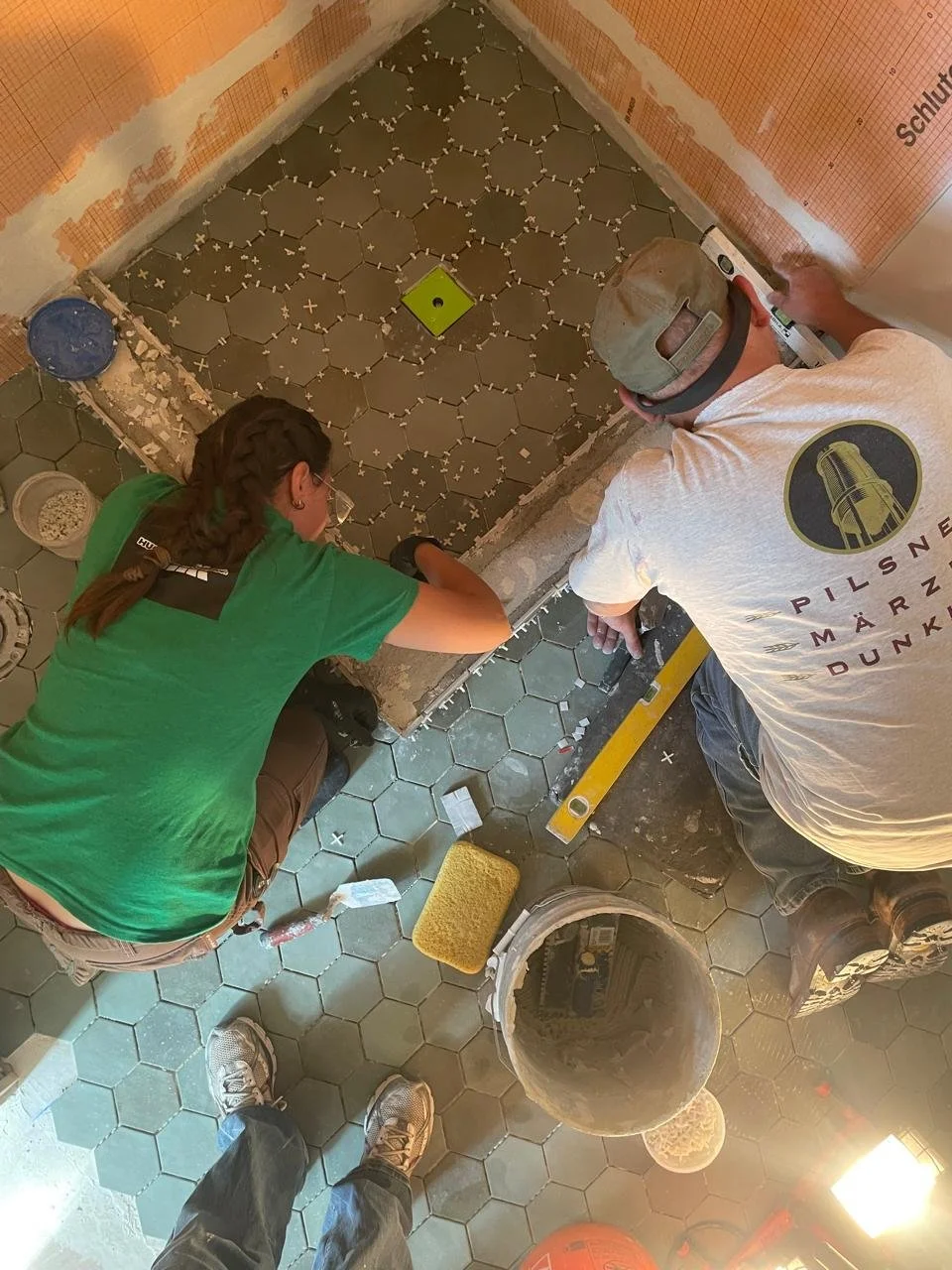 Professional tile installers setting hexagon porcelain shower floor tile during a custom bathroom remodel in the Lake Tahoe area.