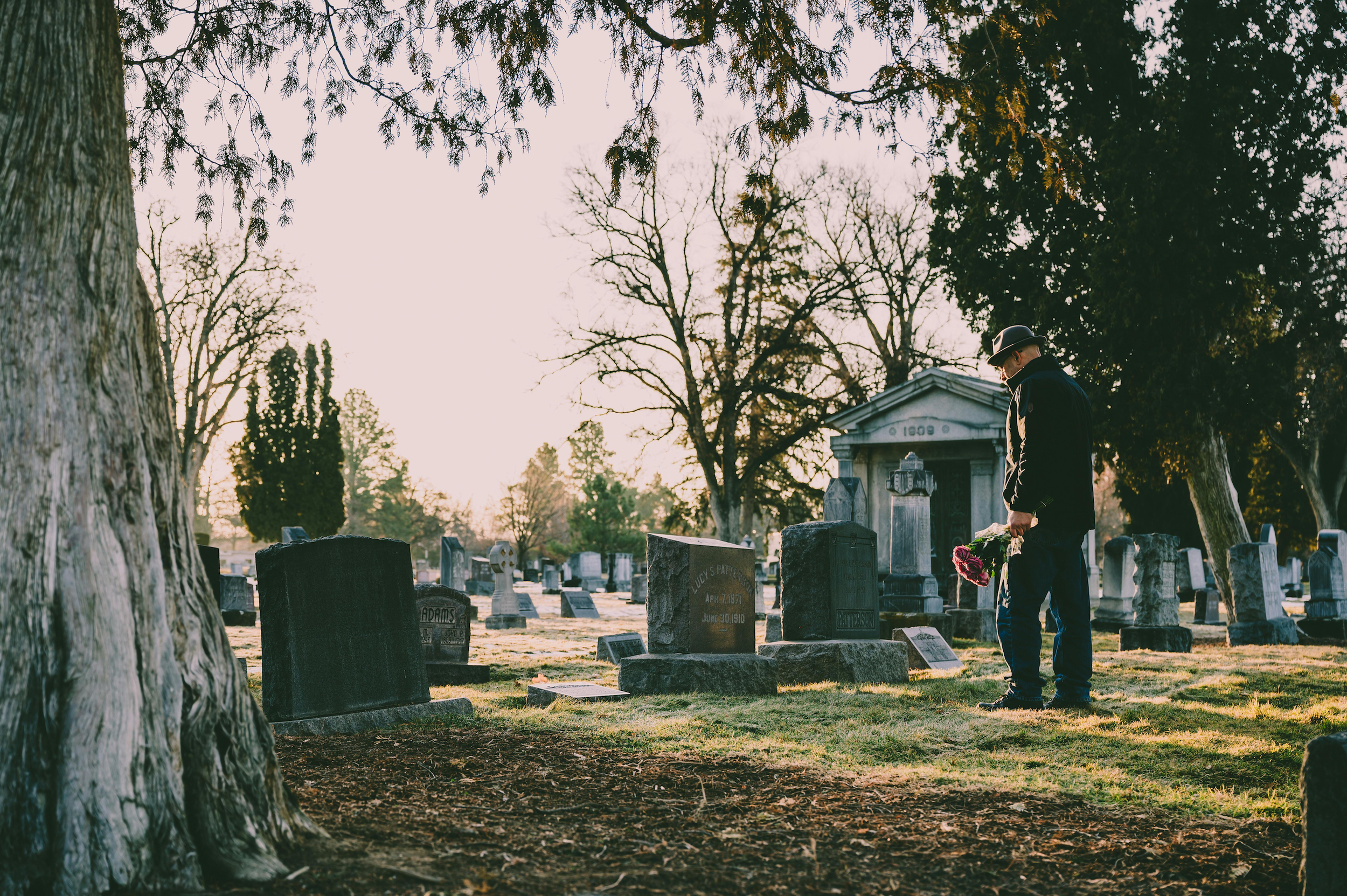 A man placing flowers on a grave, representing a certified copy of an Alameda County death certificate