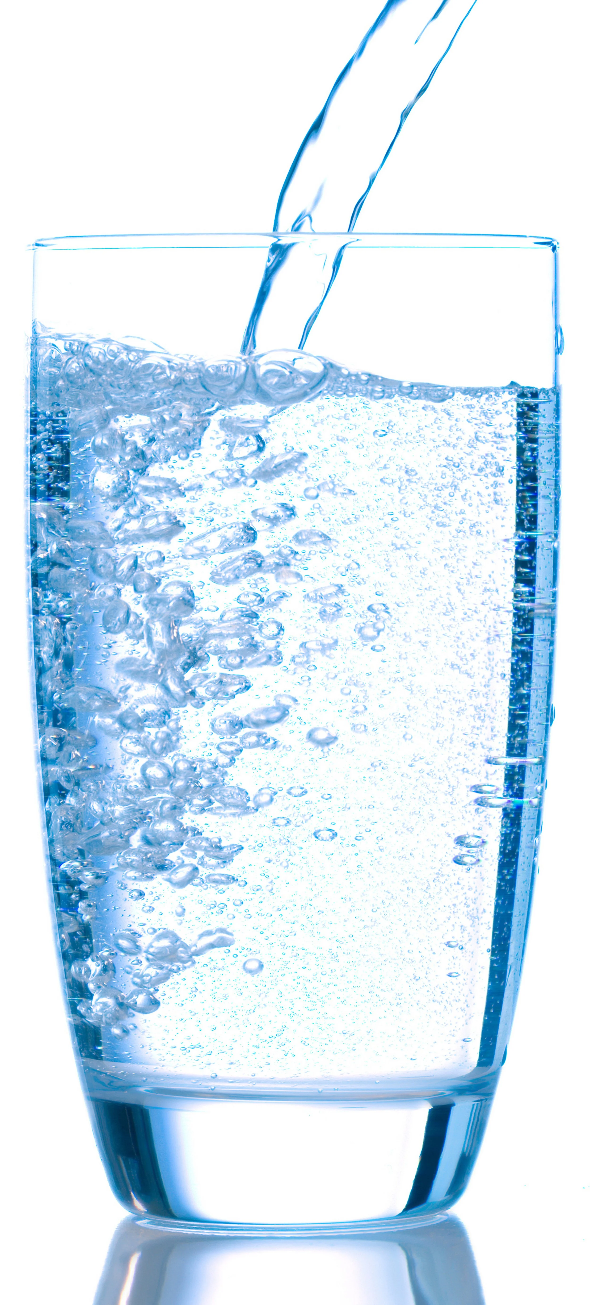A clear glass being filled with sparkling water, with bubbles visible and water pouring from above.